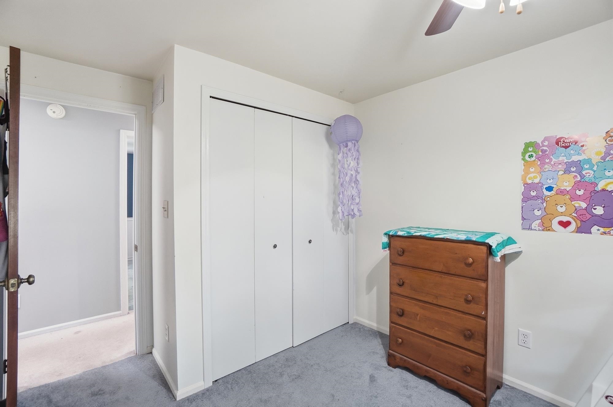 Plush carpeting, a ceiling fan, and a bi-fold closet door