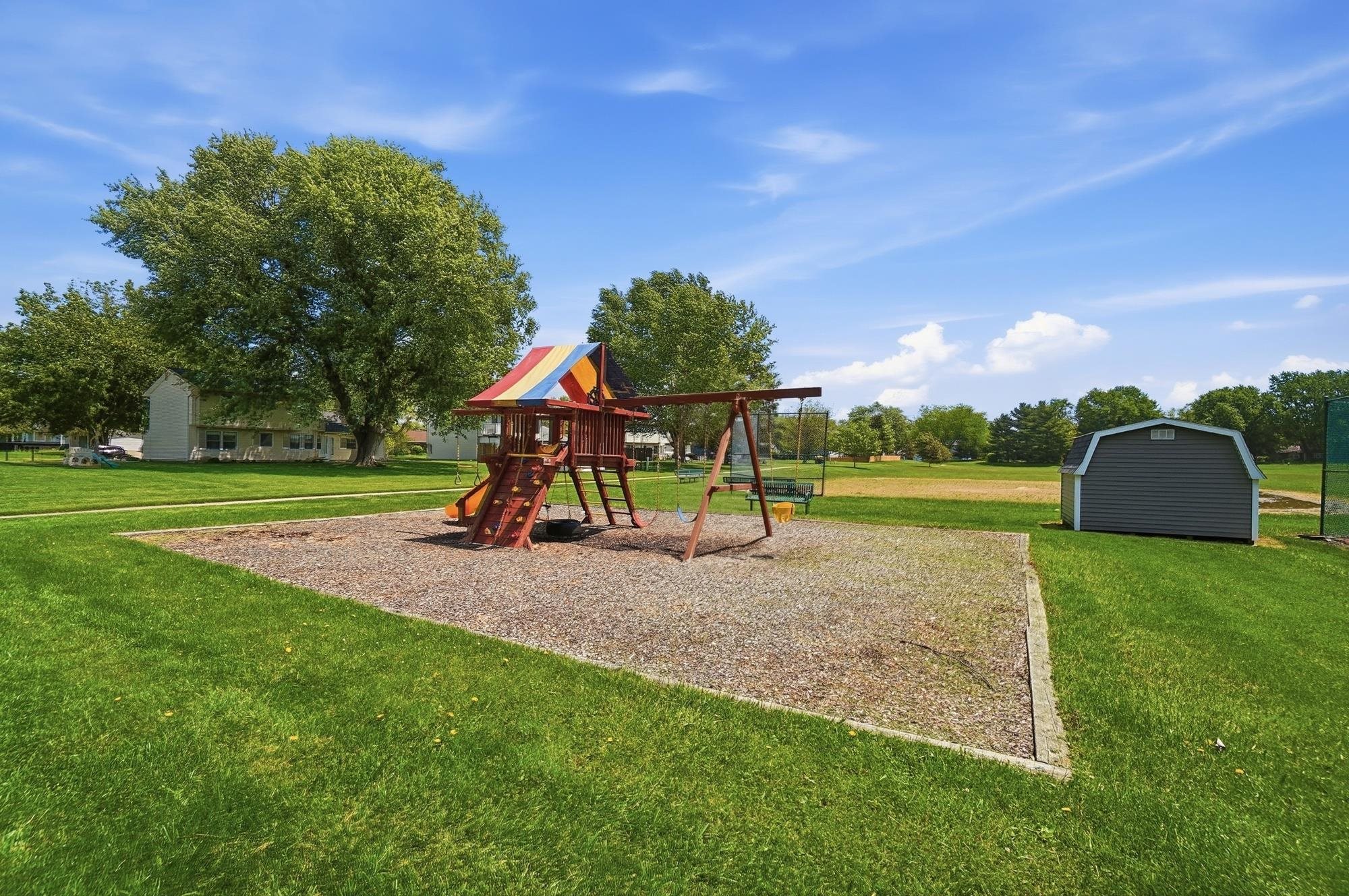 Outdoor play structure featuring a slide, swings, and multi-colored canopy