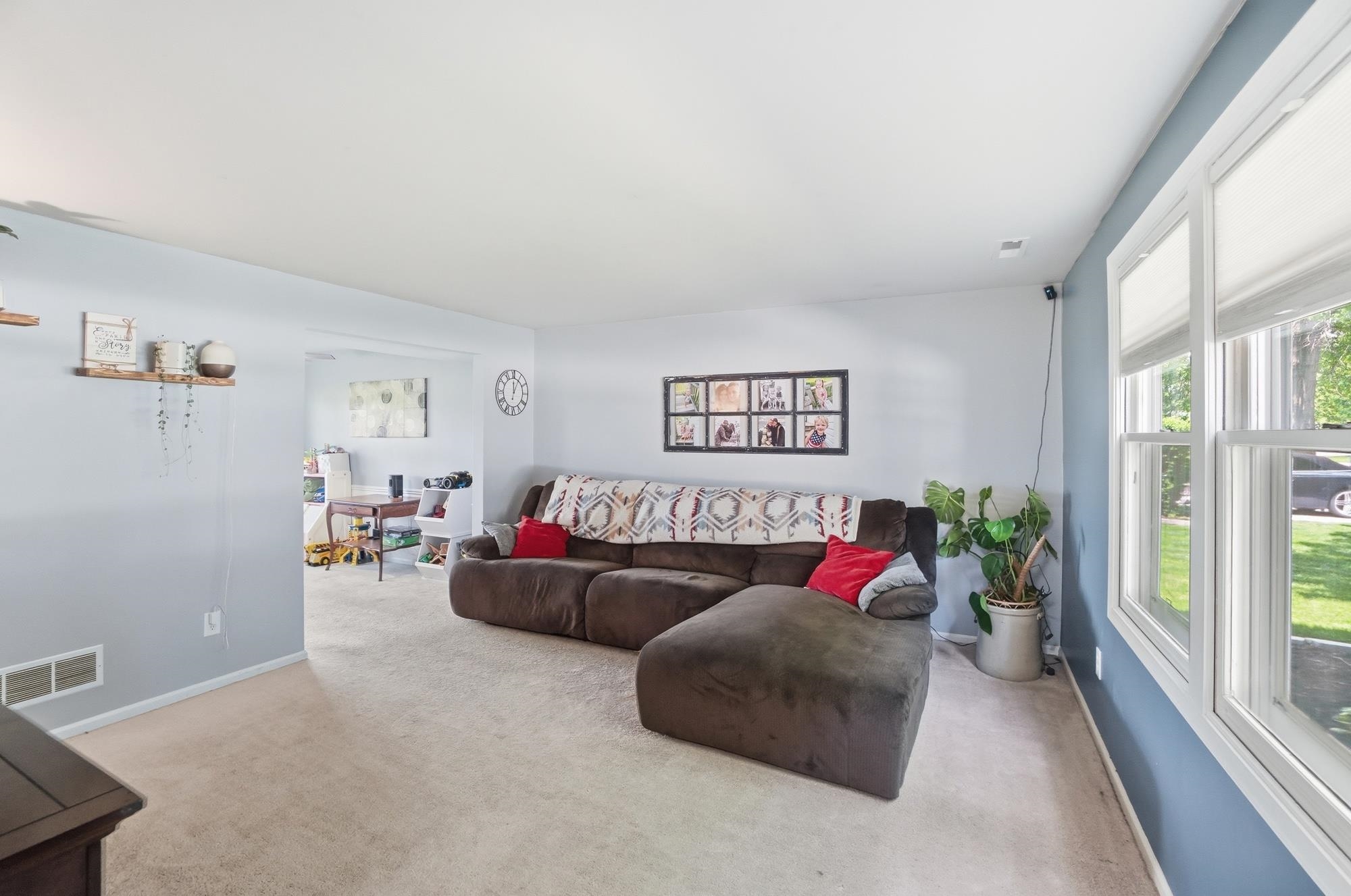 Living area featuring light-colored carpeting and a contrasting accent wall with white trim