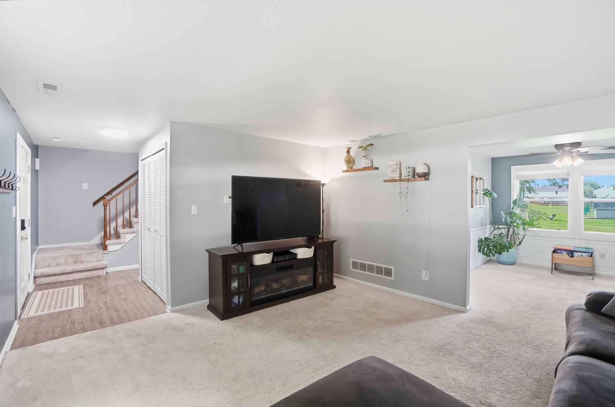 Spacious living area featuring light gray wall paint, carpeting, and a built-in entertainment console