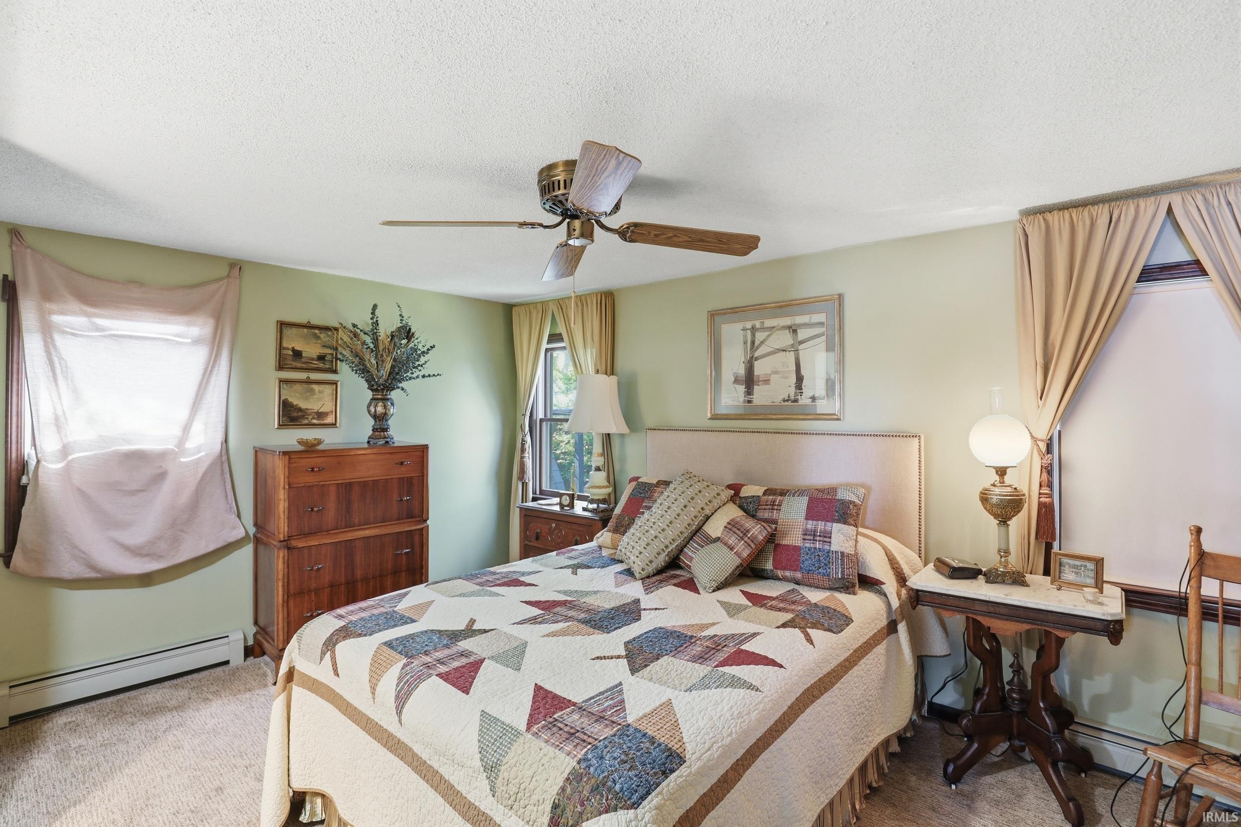 Carpeted room featuring light green walls, a white ceiling, and two windows with drapes