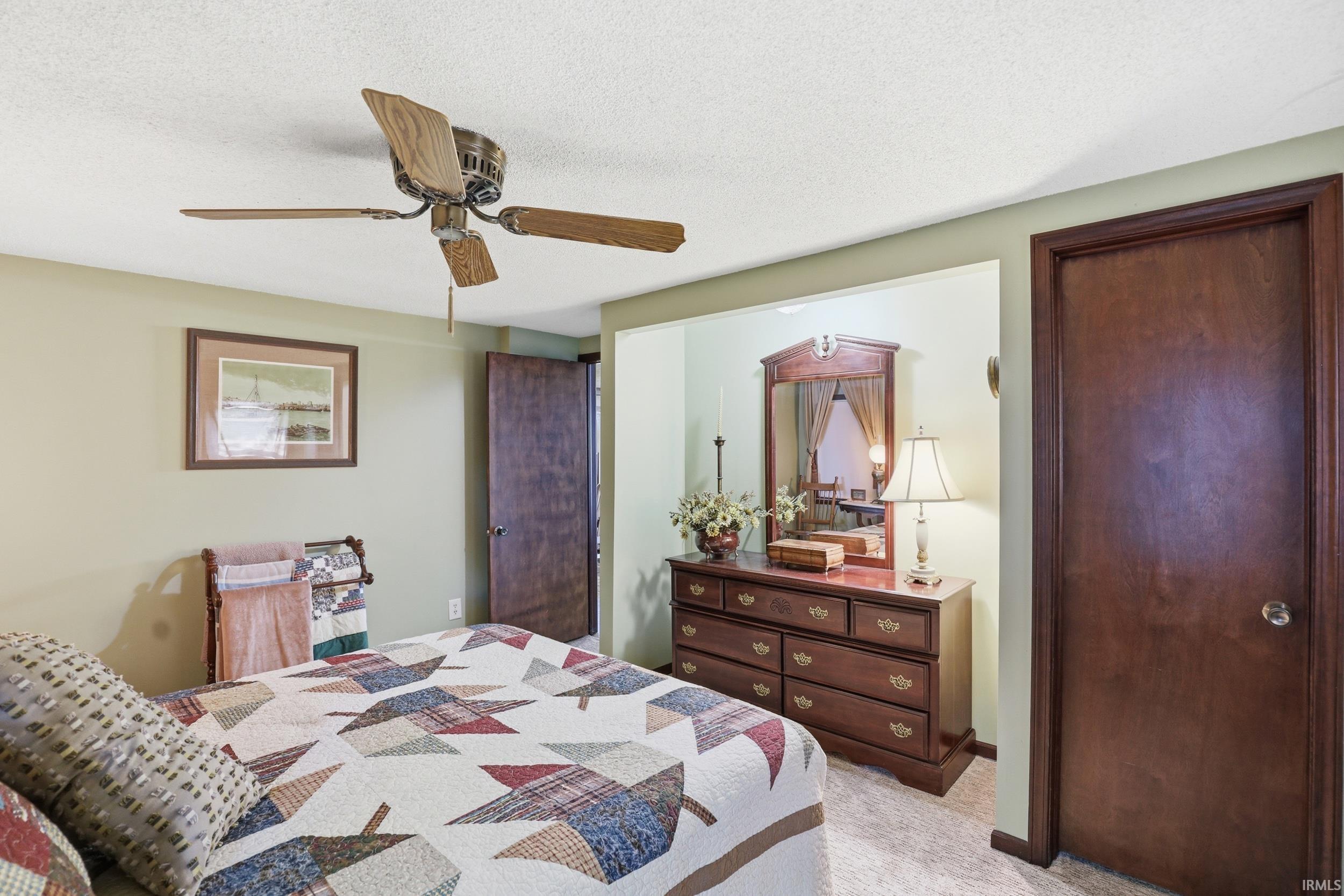 Room with wood-finish ceiling fan, wood-trim doorway, wall-to-wall carpeting, and light green painted walls