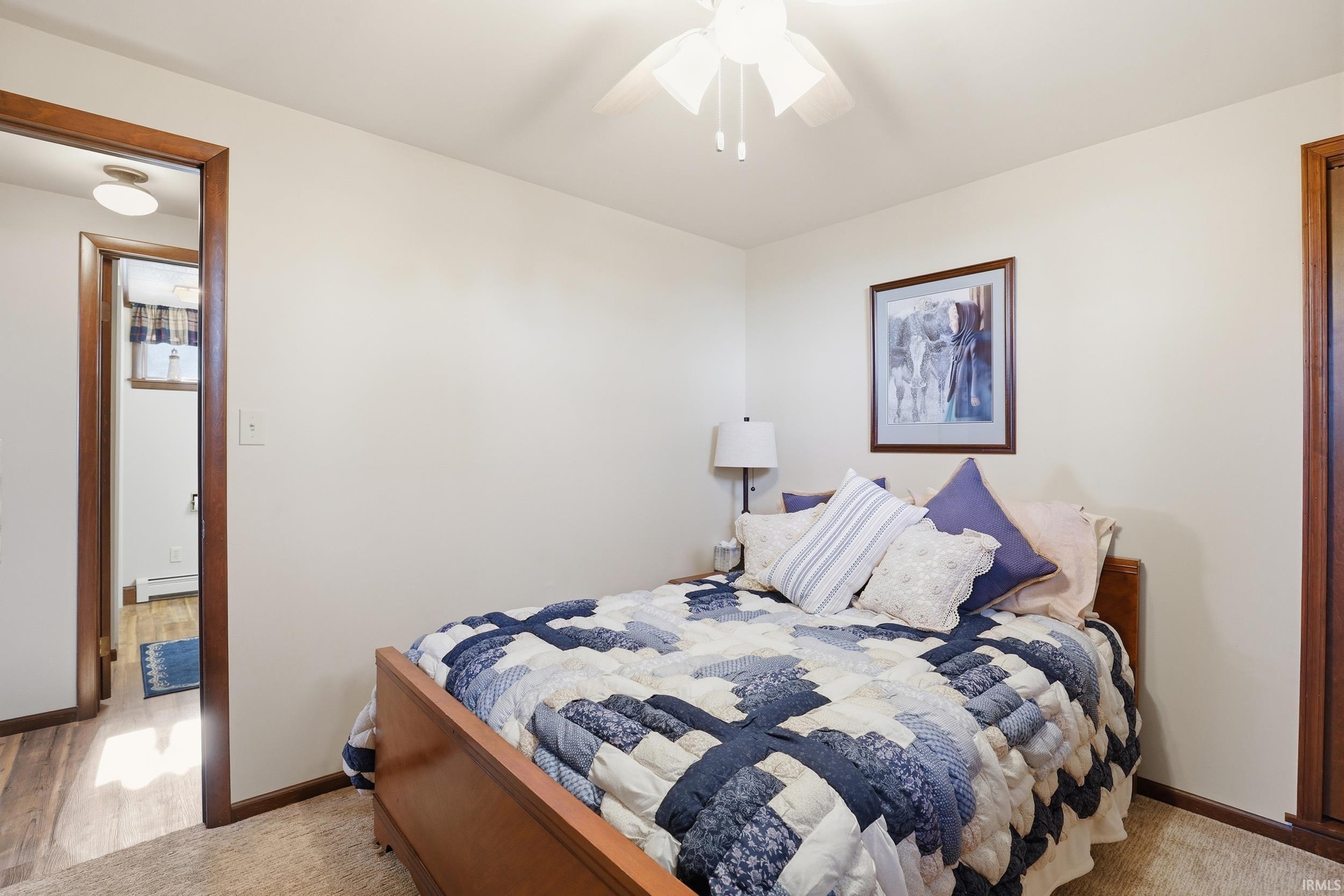Bedroom featuring light-toned walls, a white ceiling fan, and carpeted flooring