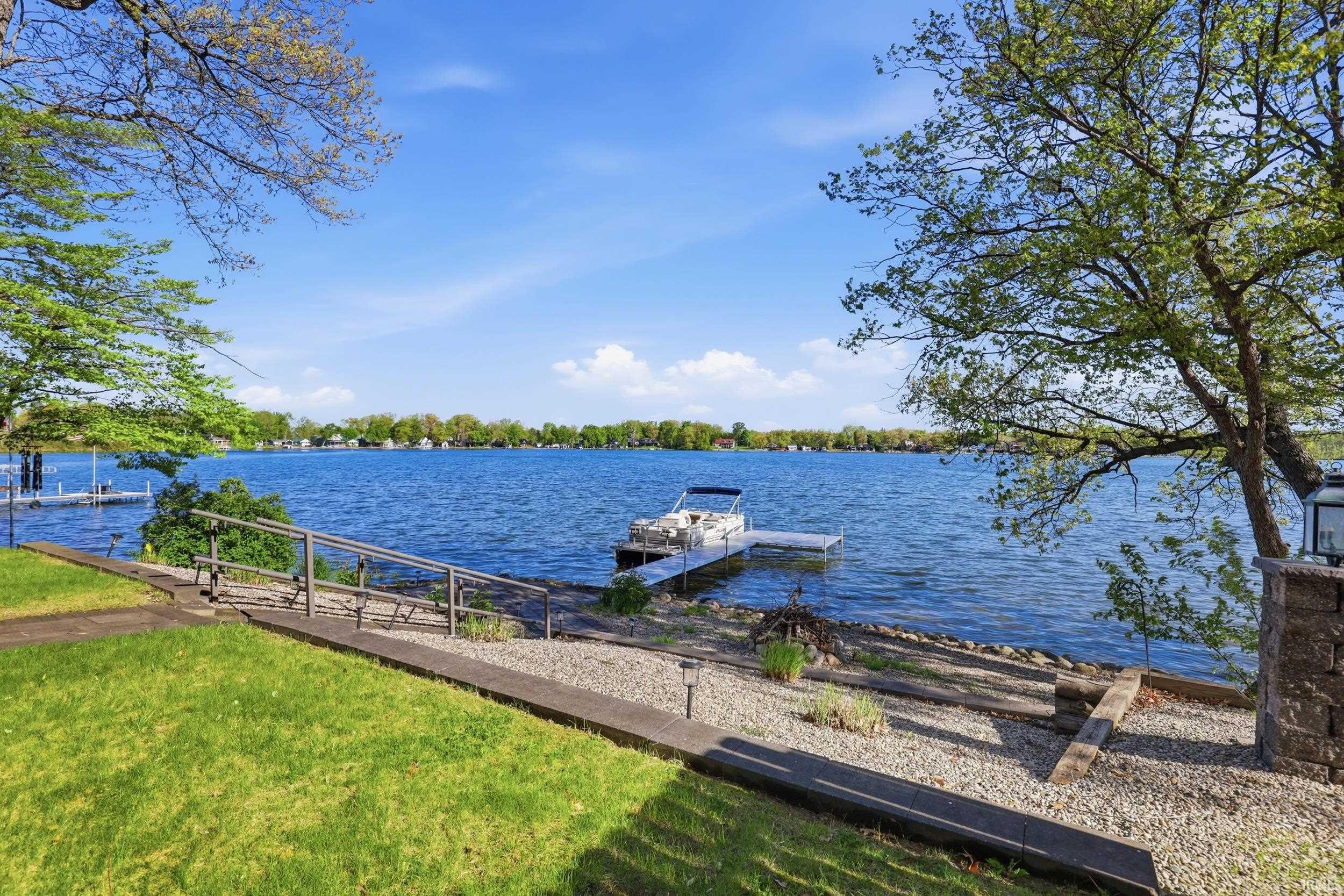 Expansive waterfront featuring a private boat dock, clear blue waters, and lush green landscaping