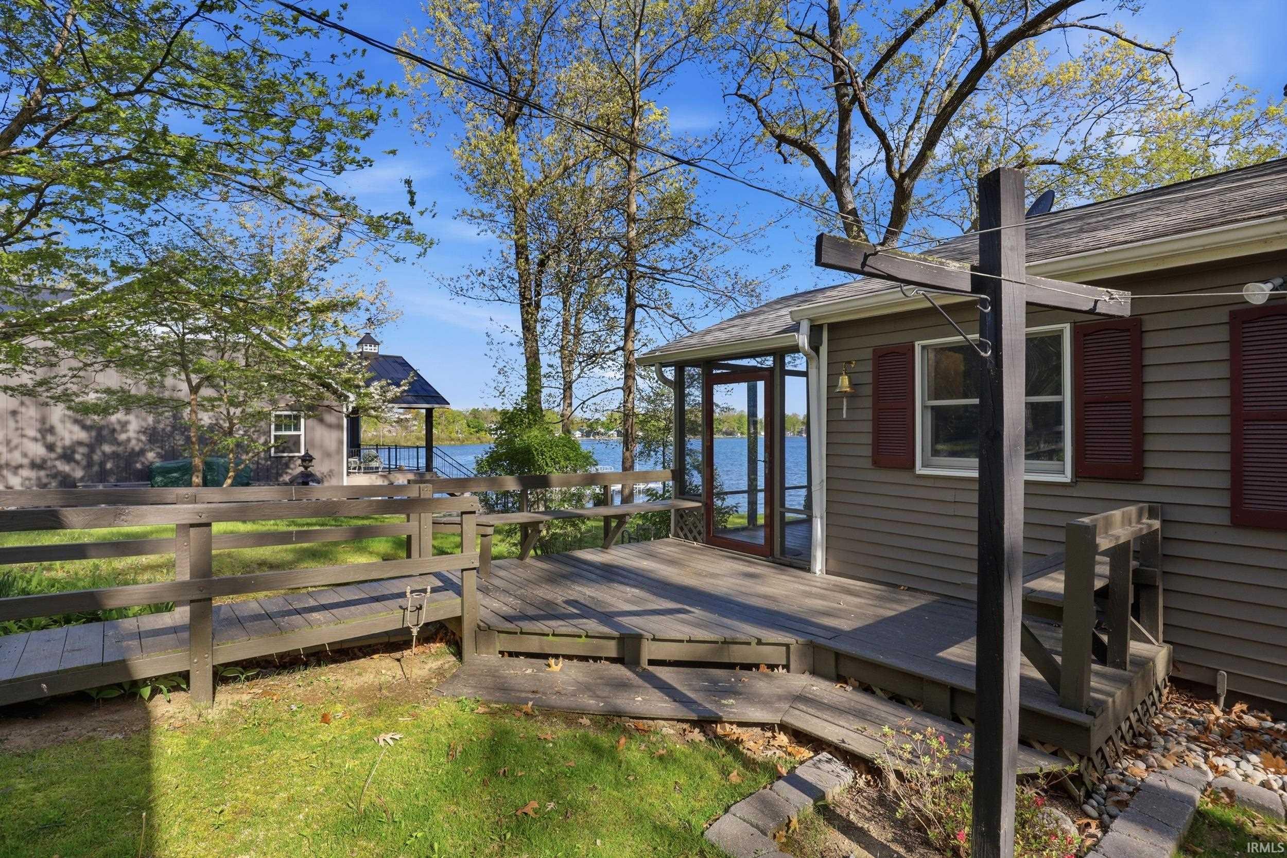 Exterior deck with a ramp entry, screened porch, and water backdrop