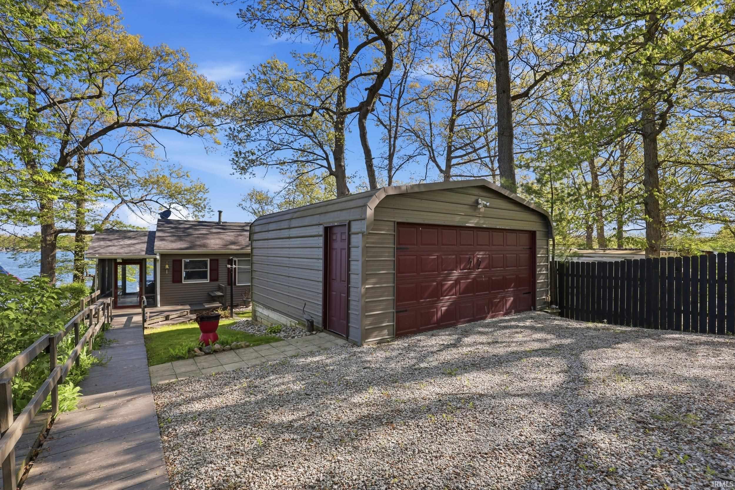 Detached garage with a paneled door, offering convenient access from the gravel driveway