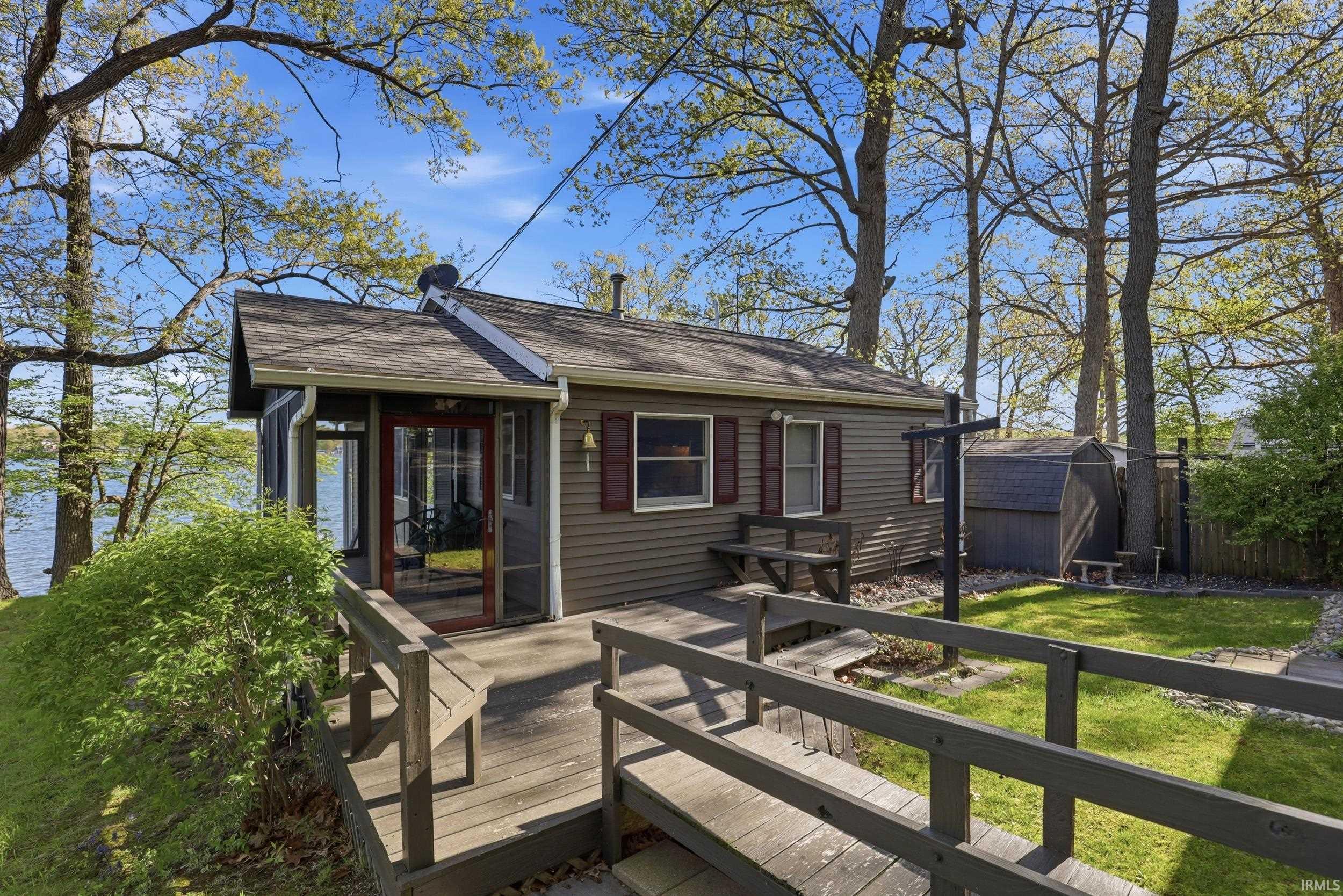 Waterfront property featuring a screened porch, an expansive wooden deck, and a dedicated storage shed