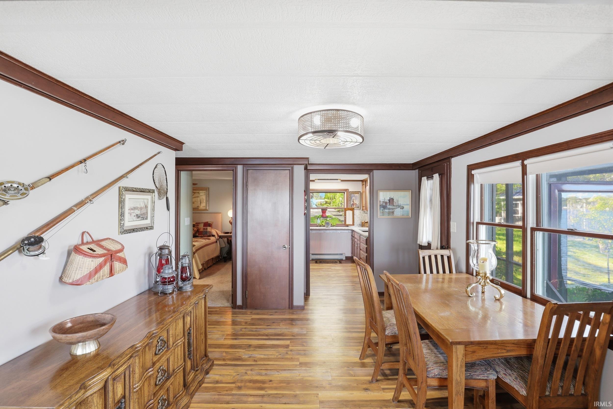 Dining area featuring wood-finish flooring, a contemporary ceiling light fixture, and windows with roller shades