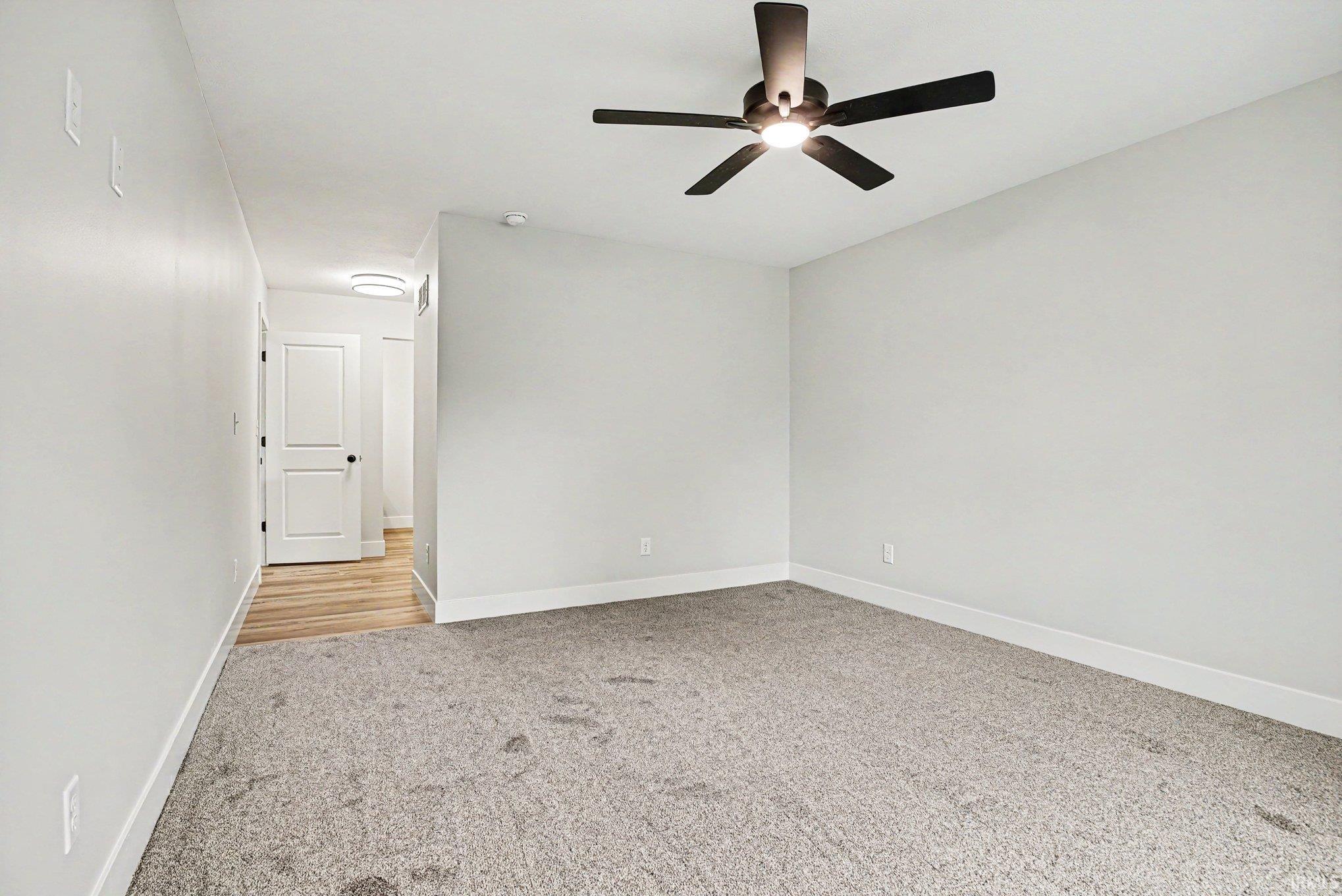 Spacious room with light gray walls and gray carpet flooring