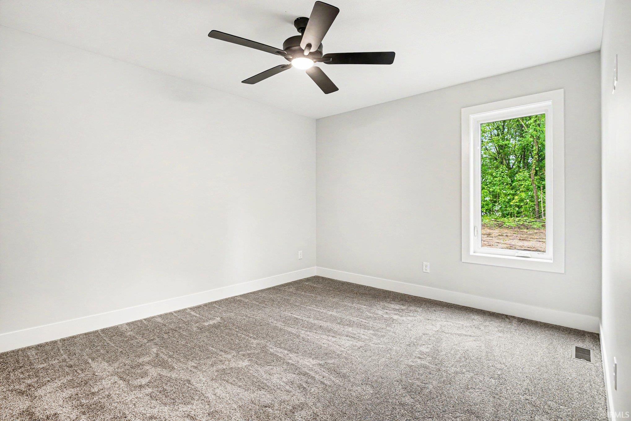 Carpeted room featuring a ceiling fan with light, a white framed window, and light gray wall paint