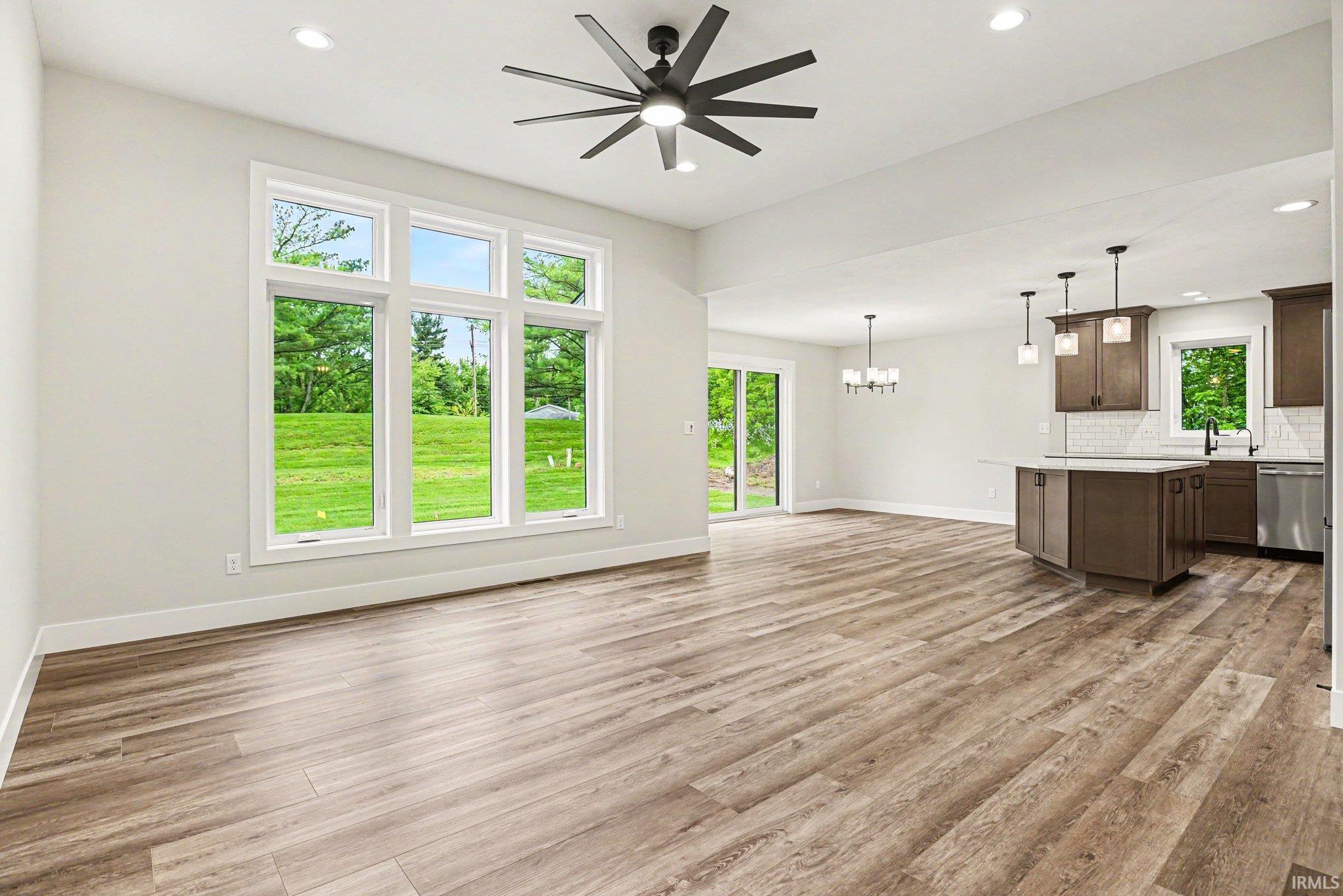 Spacious room featuring wood-finish flooring, a contemporary ceiling fan, and recessed lighting
