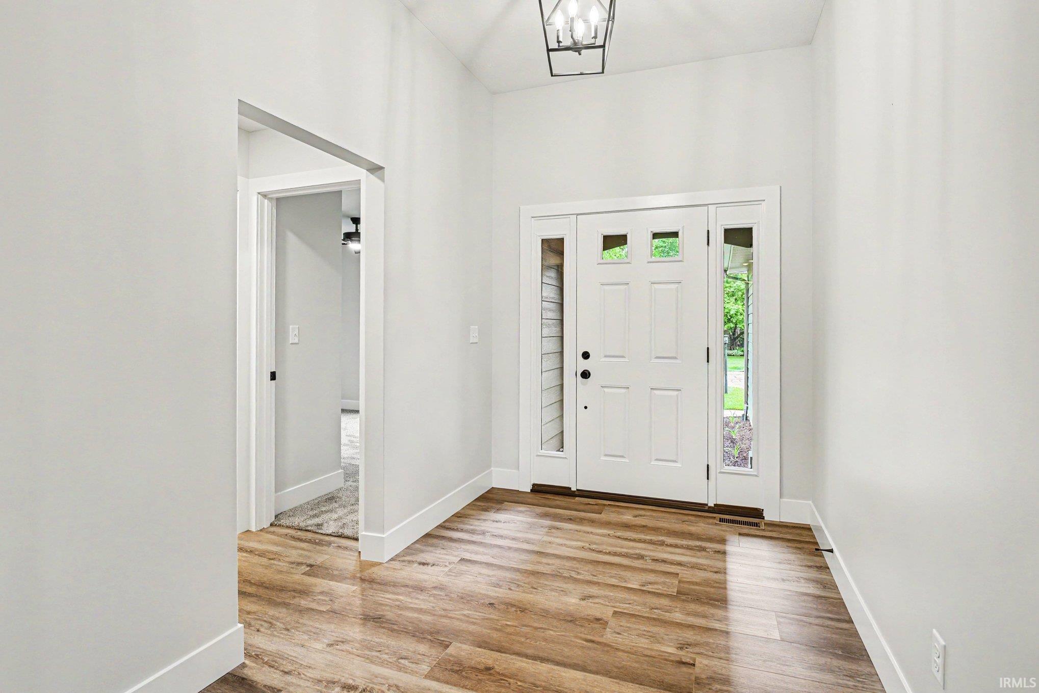 Foyer entry featuring a white paneled door with glass inserts, sidelight windows, and a black geometric ceiling light fixture