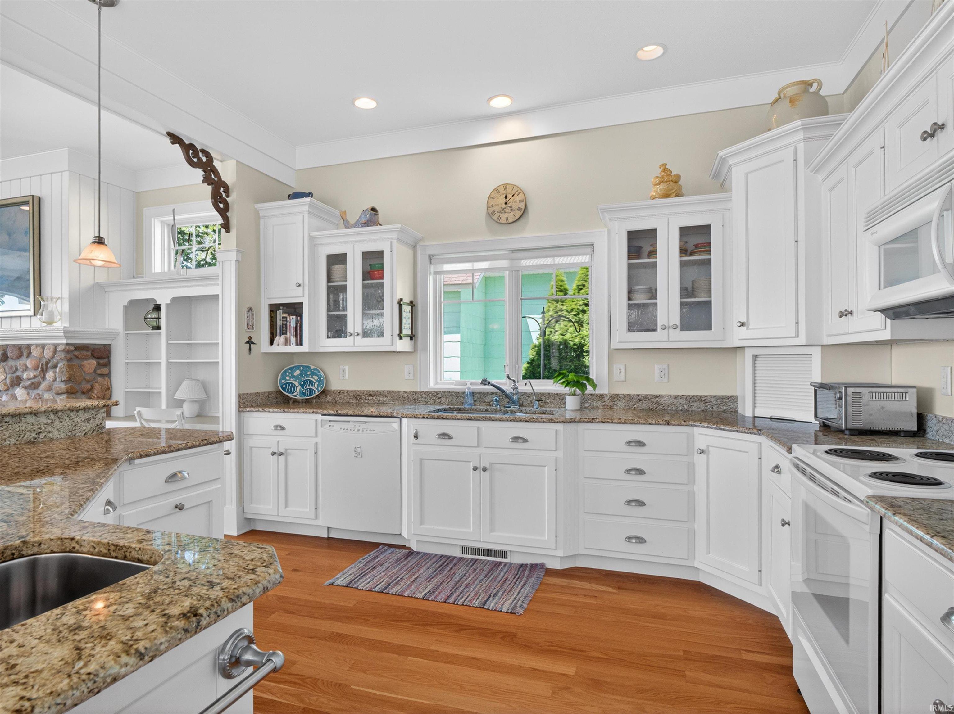 Kitchen featuring white cabinetry, granite countertops, hardwood flooring, and a stainless steel sink