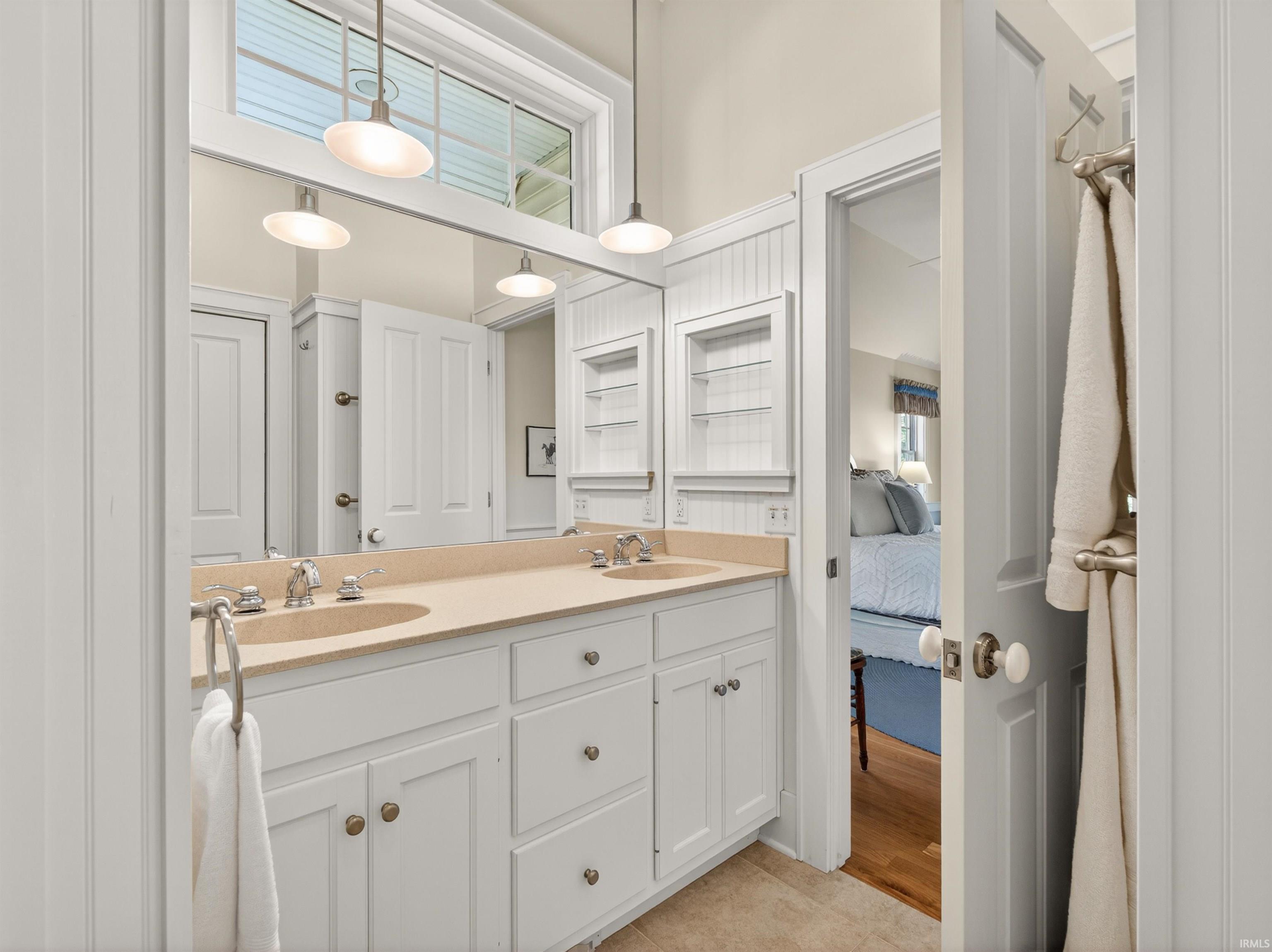 Double vanity featuring integrated sinks, light-colored countertop, and white cabinetry