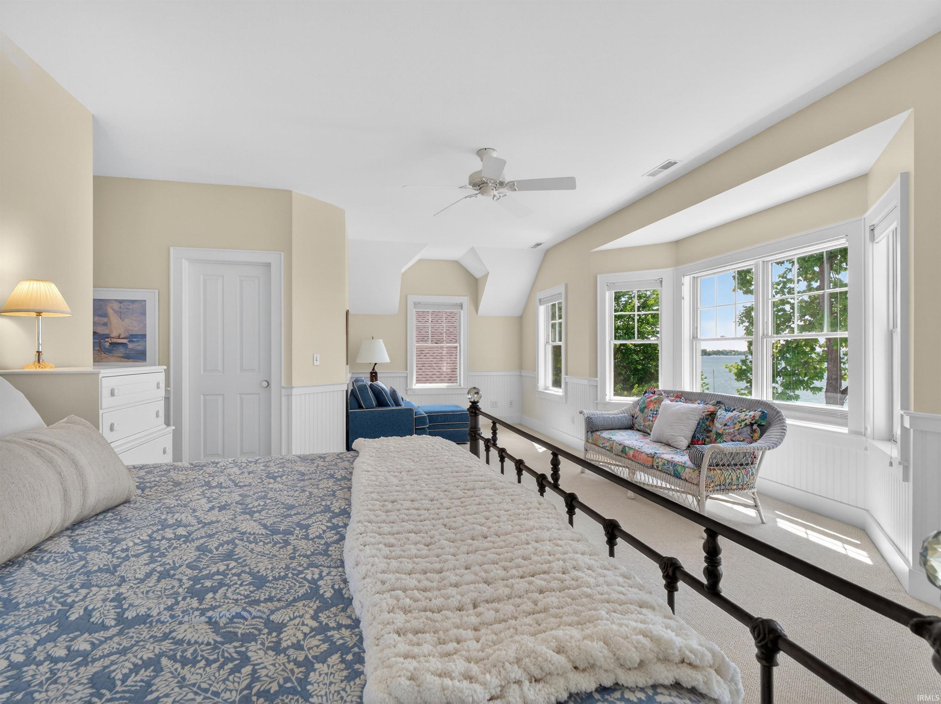 Carpeted room featuring a ceiling fan, a white paneled door, light-toned walls, and multiple windows