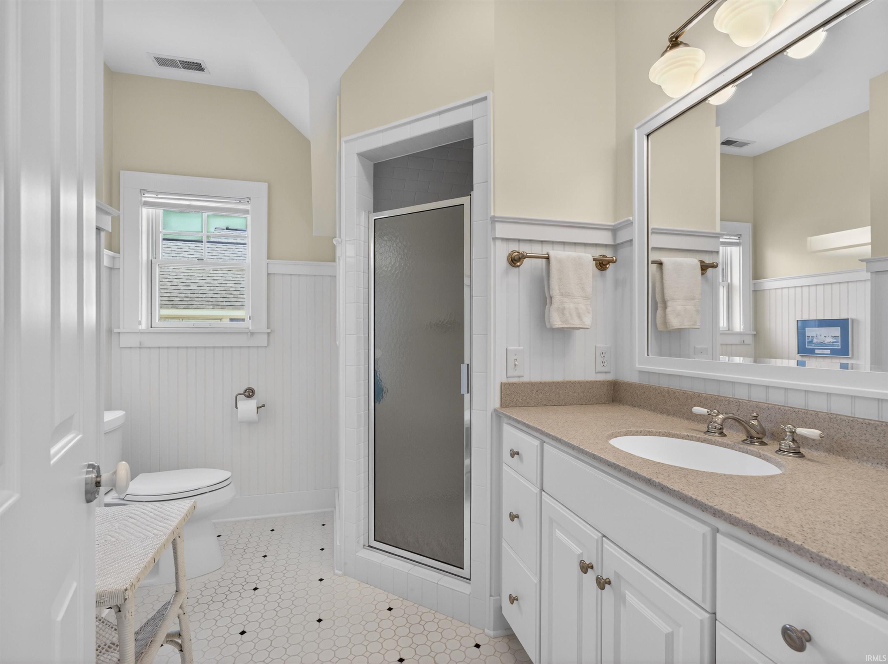 Bathroom featuring a vanity with a light-colored countertop and integrated sink, a framed mirror, and a multi-bulb light fixture