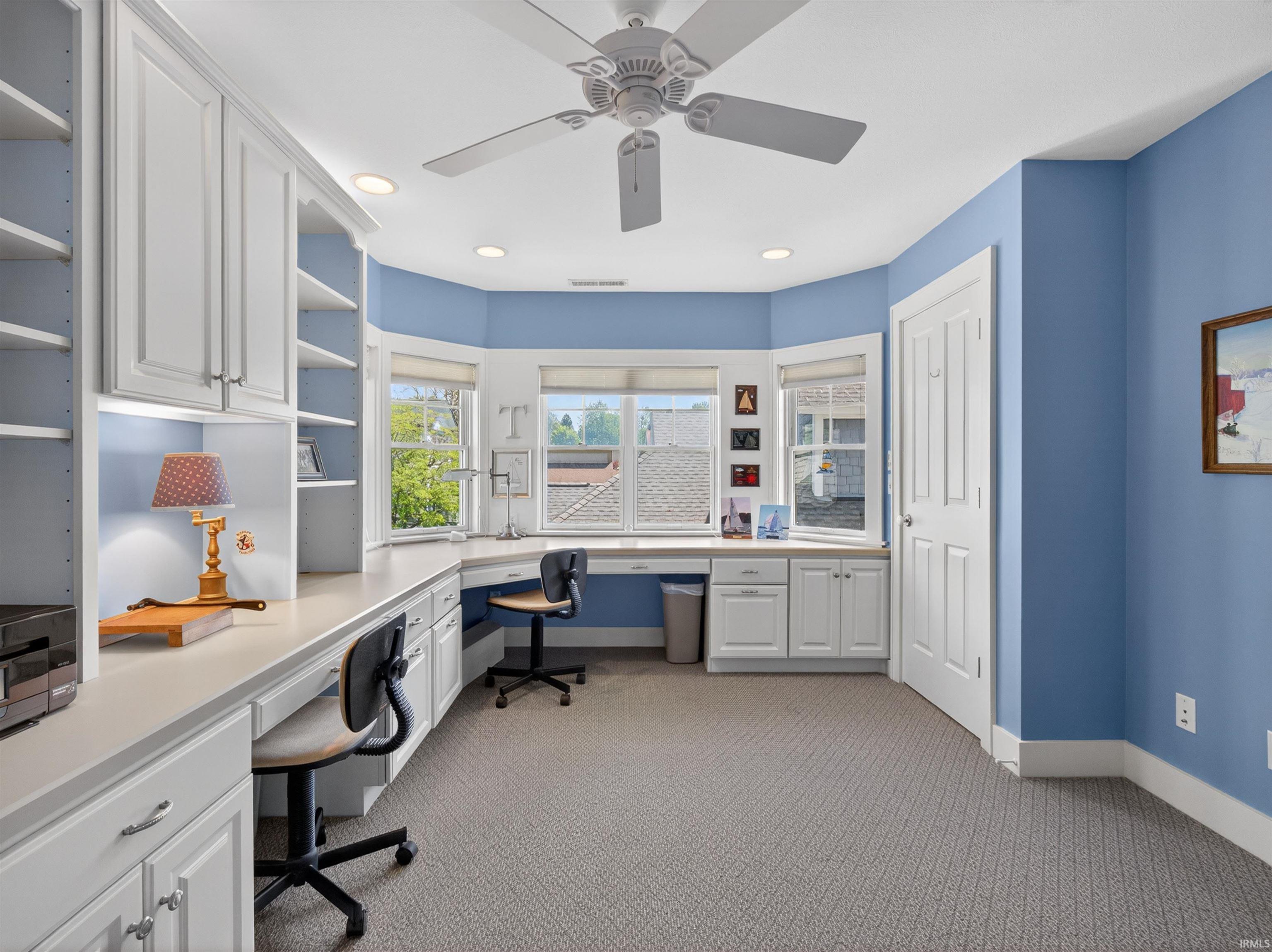 Office space featuring extensive built-in white cabinetry, integrated desk areas, recessed lighting, and a ceiling fan