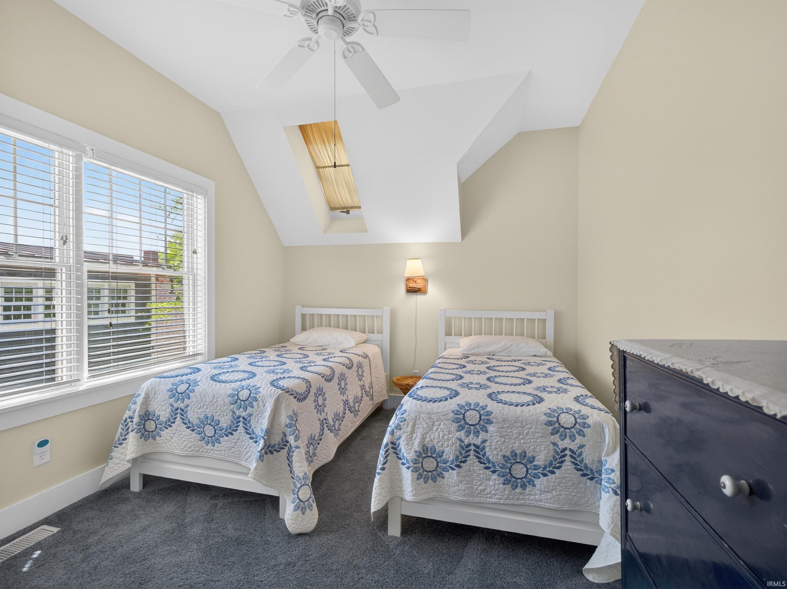 Bedroom featuring dual windows with blinds, a skylight, and a ceiling fan