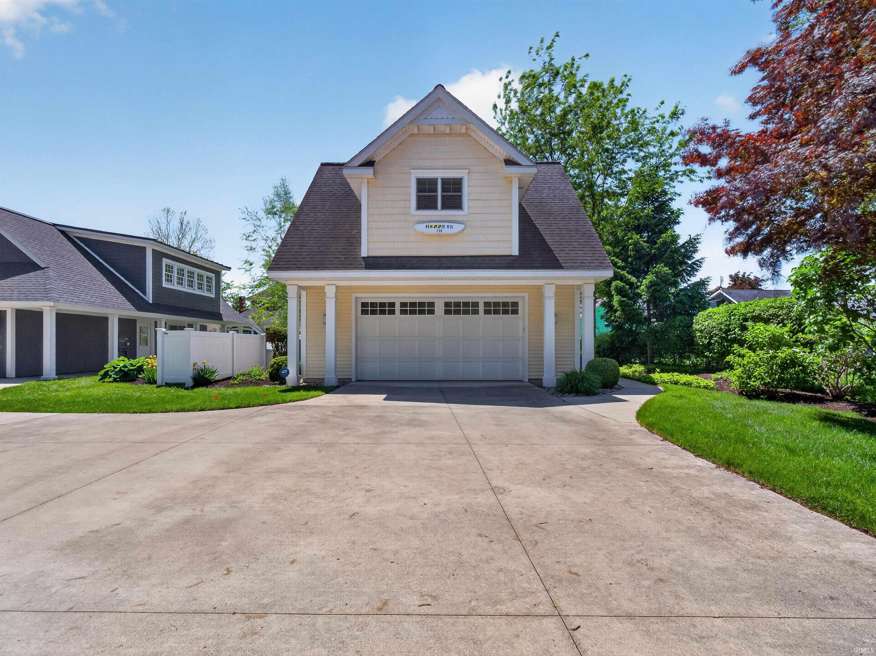 Attached garage structure featuring light yellow siding, a white garage door with window inserts, and a dark shingle roof