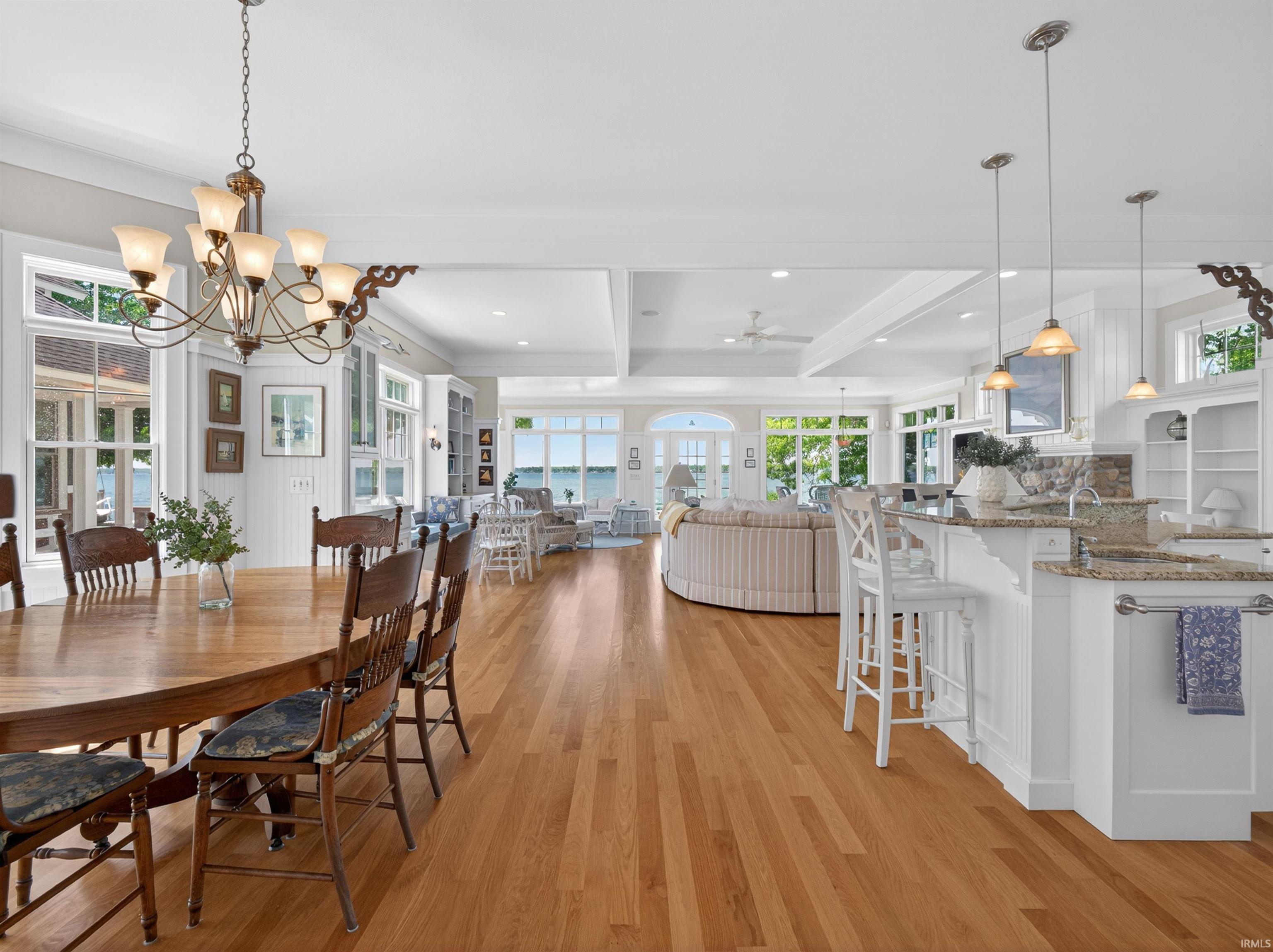 Expansive open-concept interior featuring light wood-finish flooring, white walls, and beamed ceilings