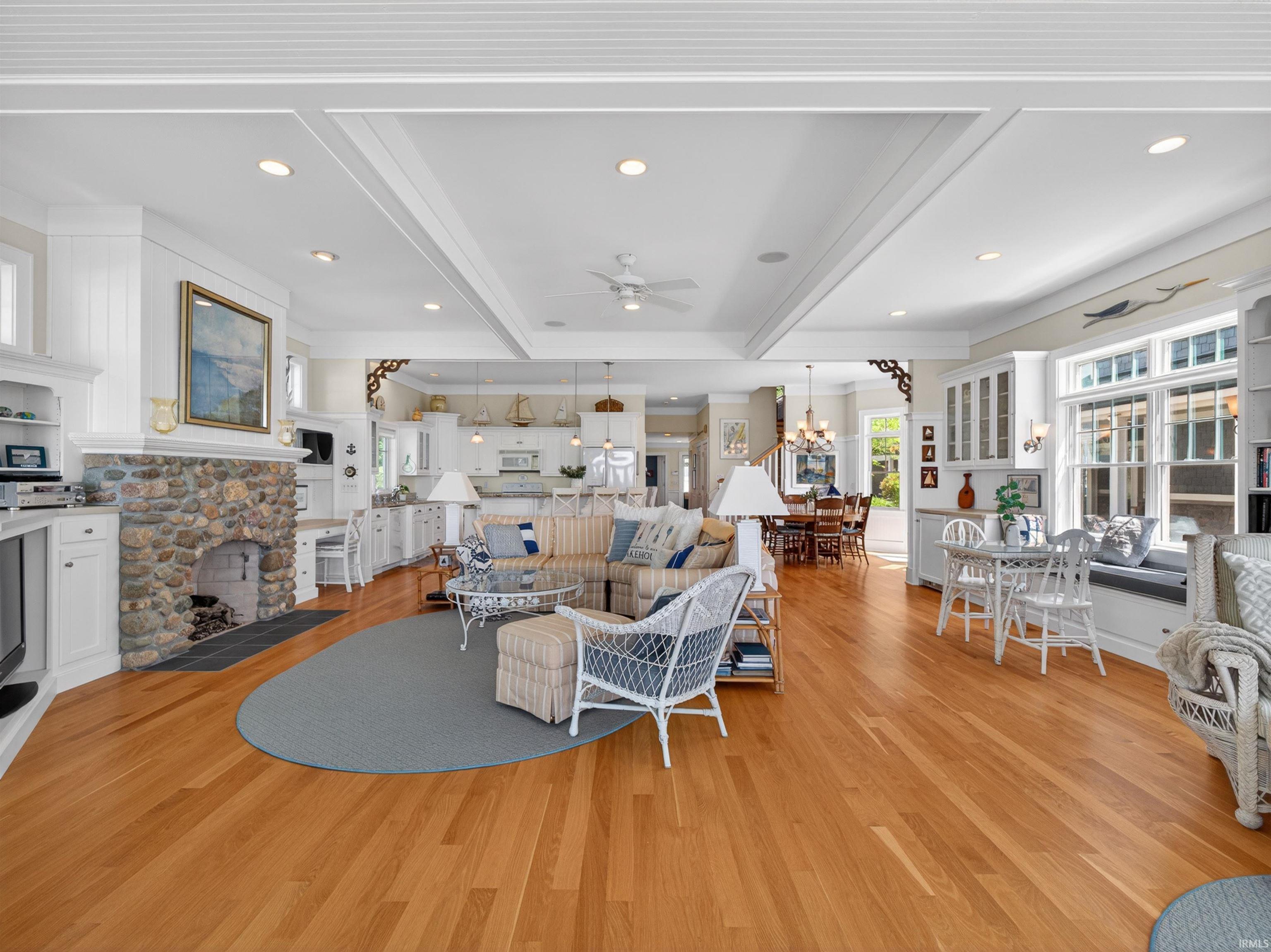 Expansive living area featuring light wood-finish flooring, a stone-faced fireplace, and built-in cabinetry