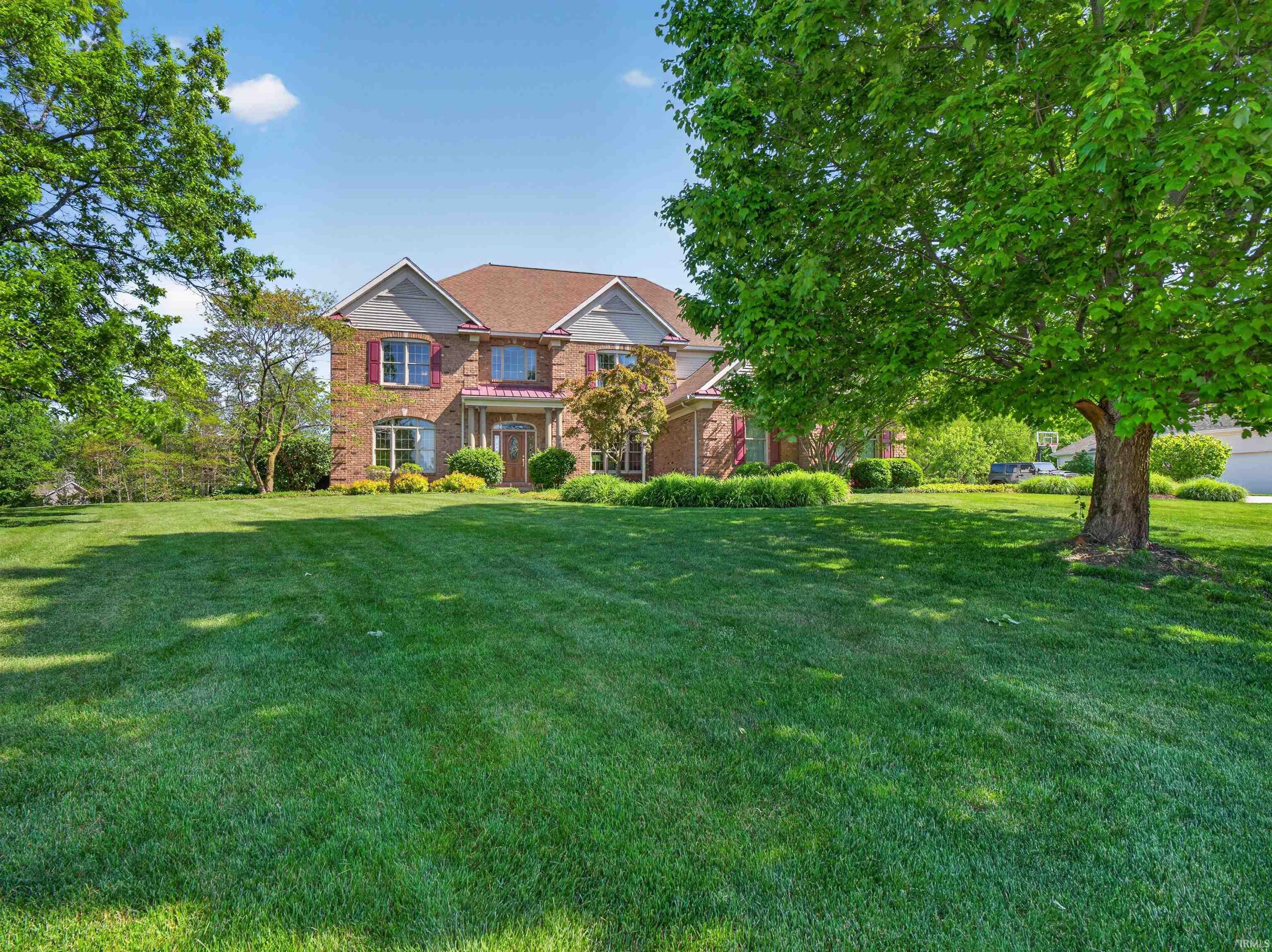 Brick and siding exterior featuring a multi-level roofline, red window shutters, and a welcoming front entrance
