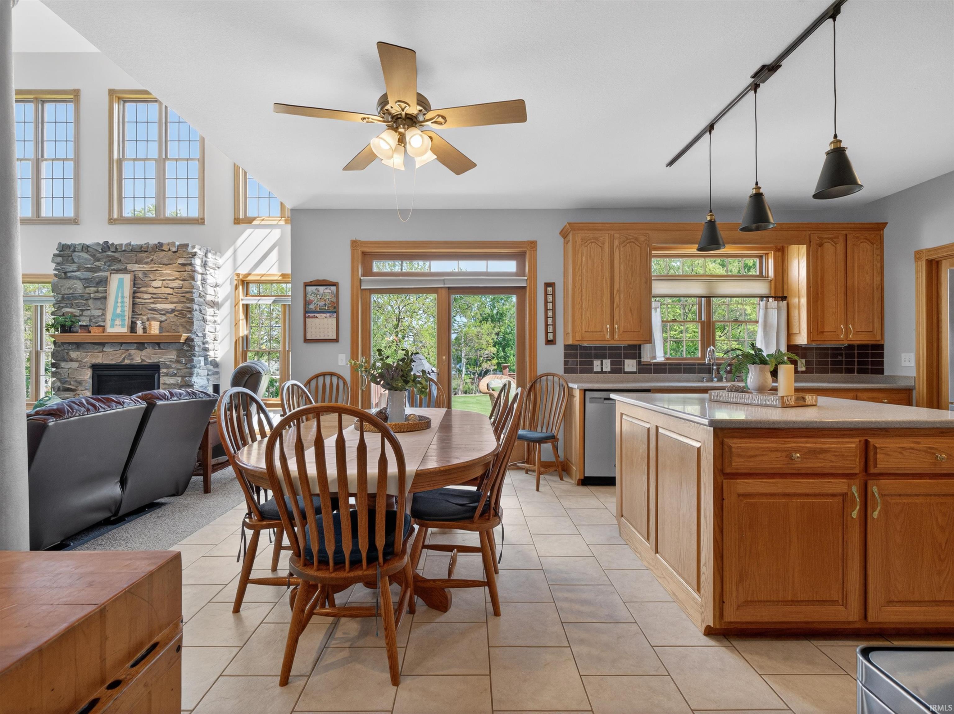 Open-concept kitchen and dining area featuring ceramic tile flooring, wood cabinetry, a center island with countertop seating, and a ceiling fan