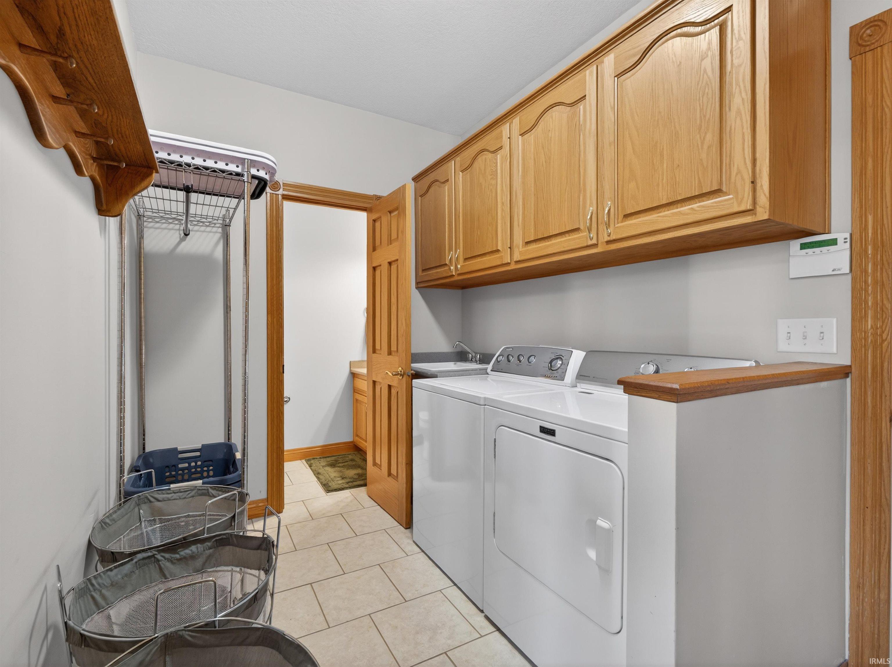 Dedicated utility room featuring light-toned cabinetry, a built-in sink, and tile flooring