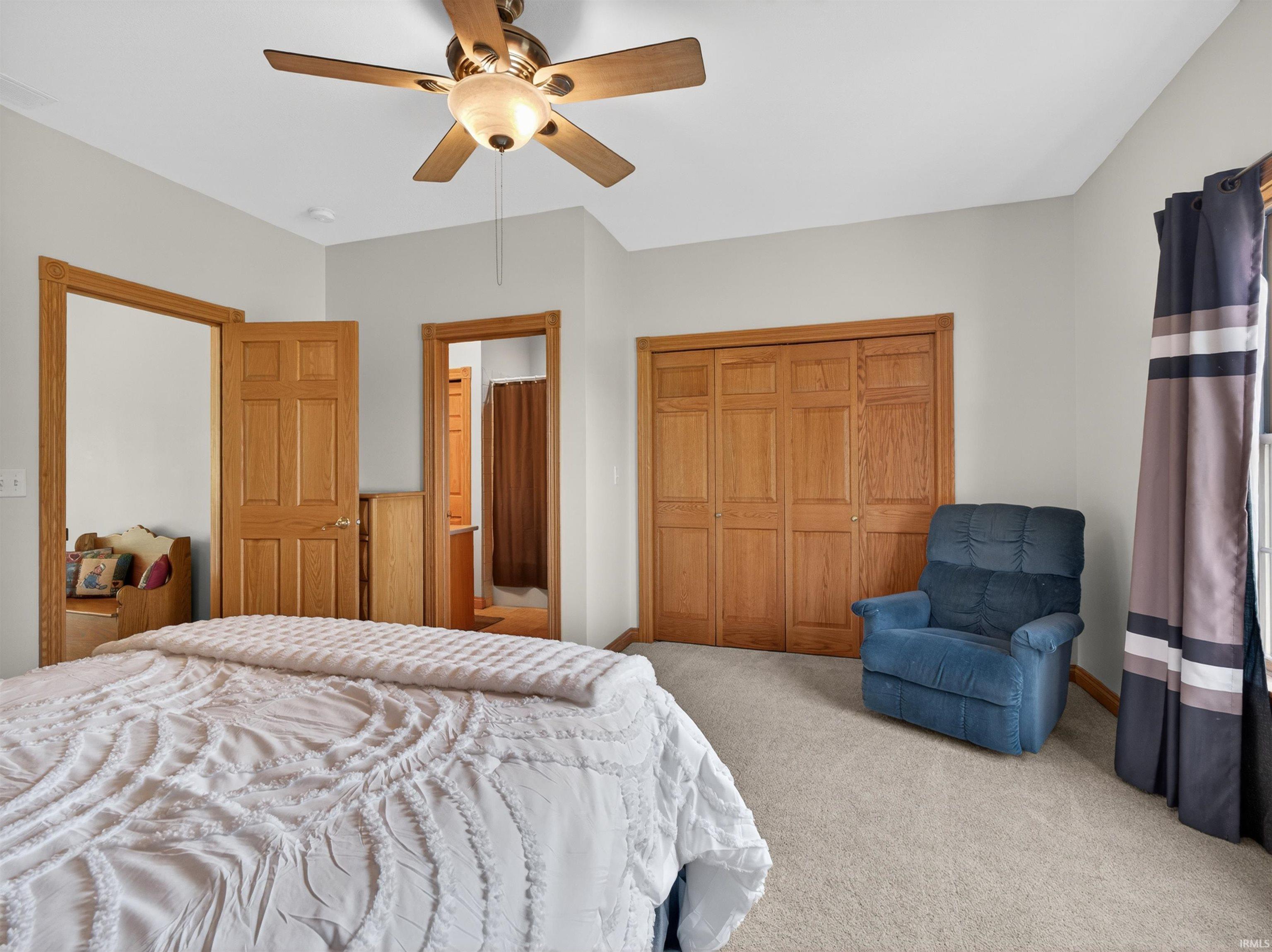 Carpeted room featuring a ceiling fan, light-colored walls, and wood-finish doors