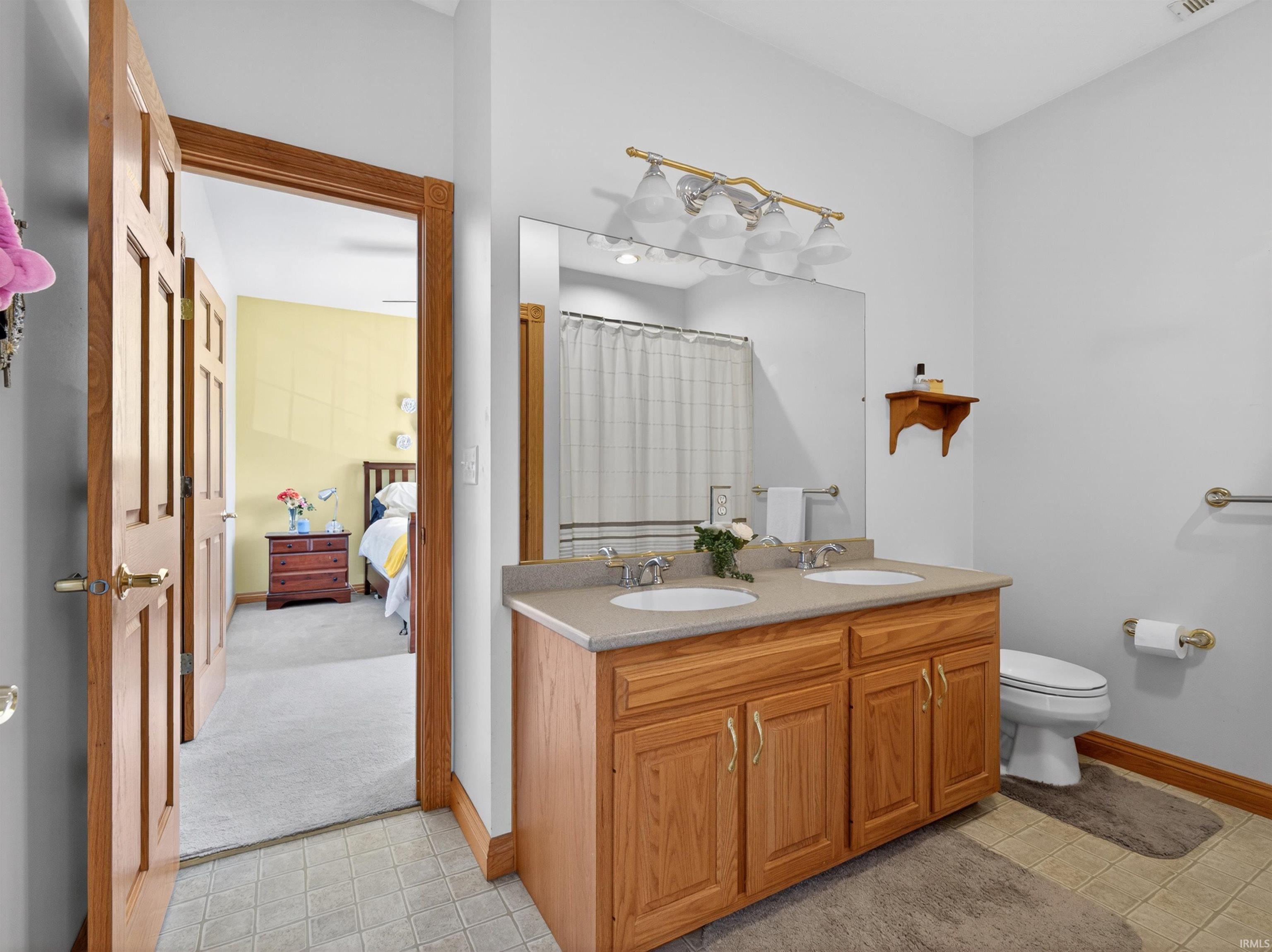 Bathroom featuring a double vanity with light wood cabinetry and a neutral-toned countertop