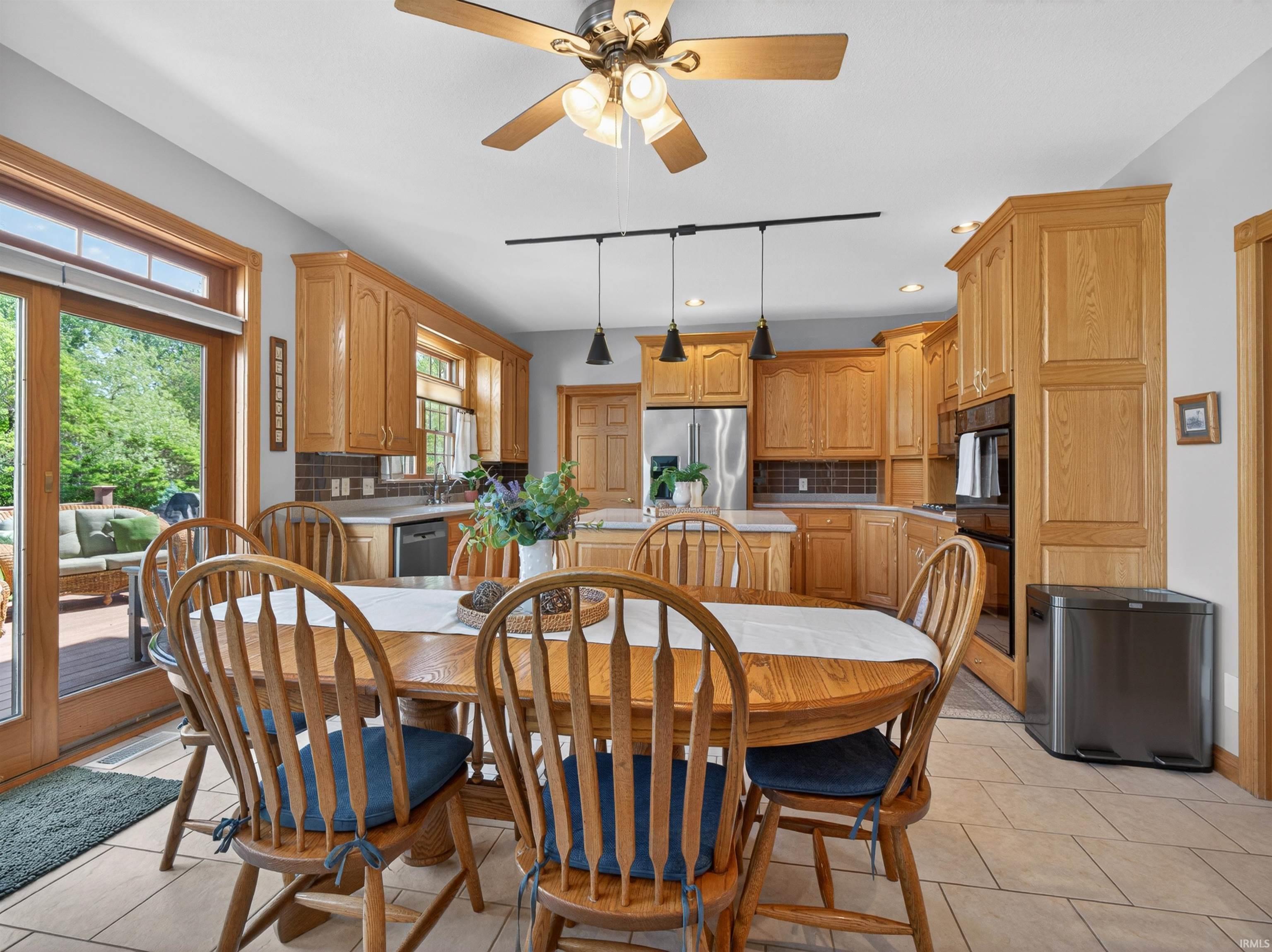 Kitchen and dining area featuring light wood cabinetry, stainless steel appliances, and a tile backsplash