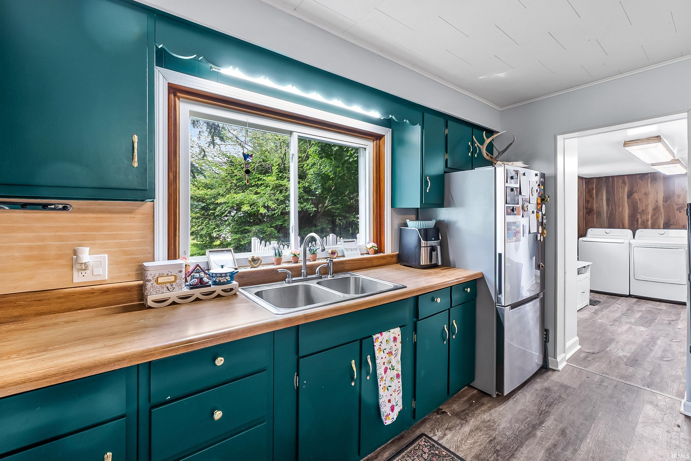 Kitchen featuring wood-finish countertops, stainless steel double-basin sink, and teal cabinetry