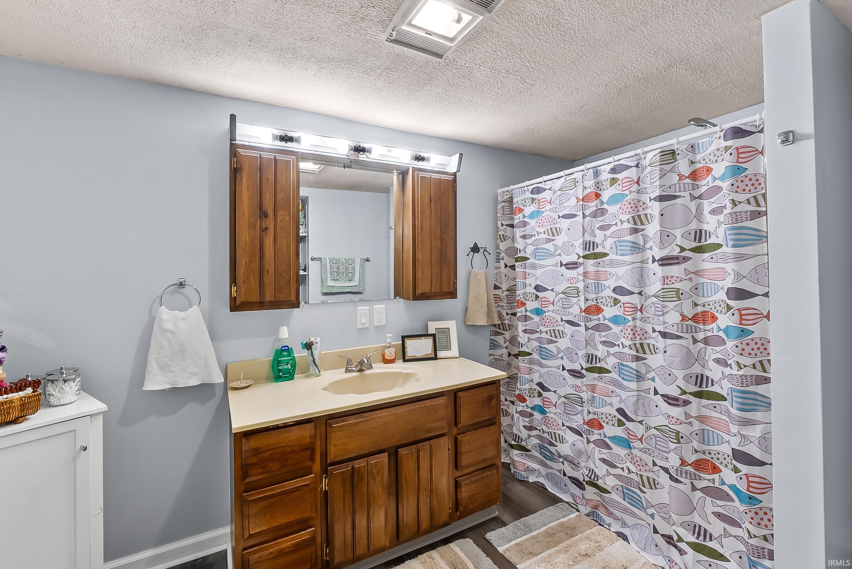 Bathroom featuring a wood-finish vanity with an integrated sink and light-toned countertop