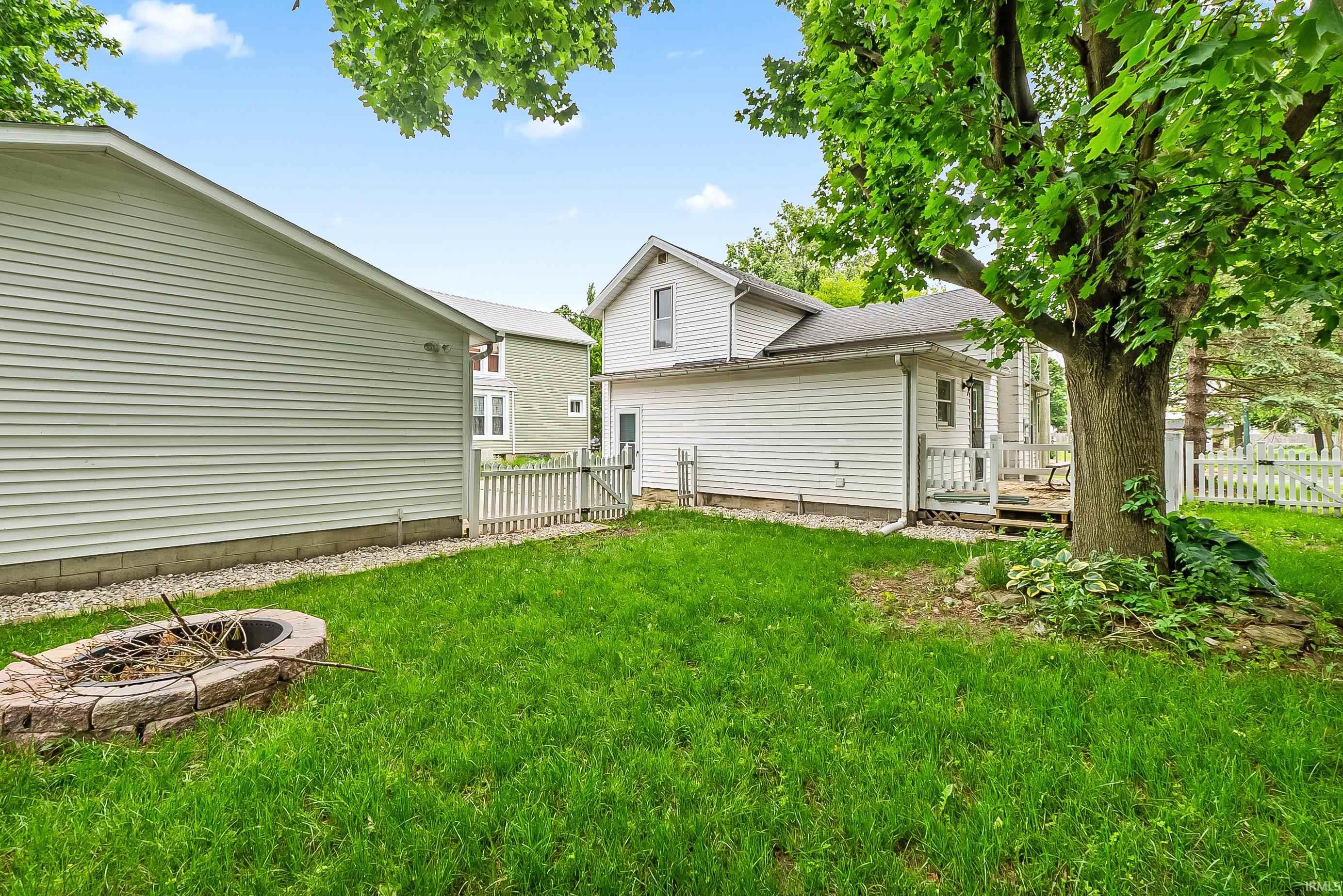 Expansive green lawn featuring a stone-lined fire pit