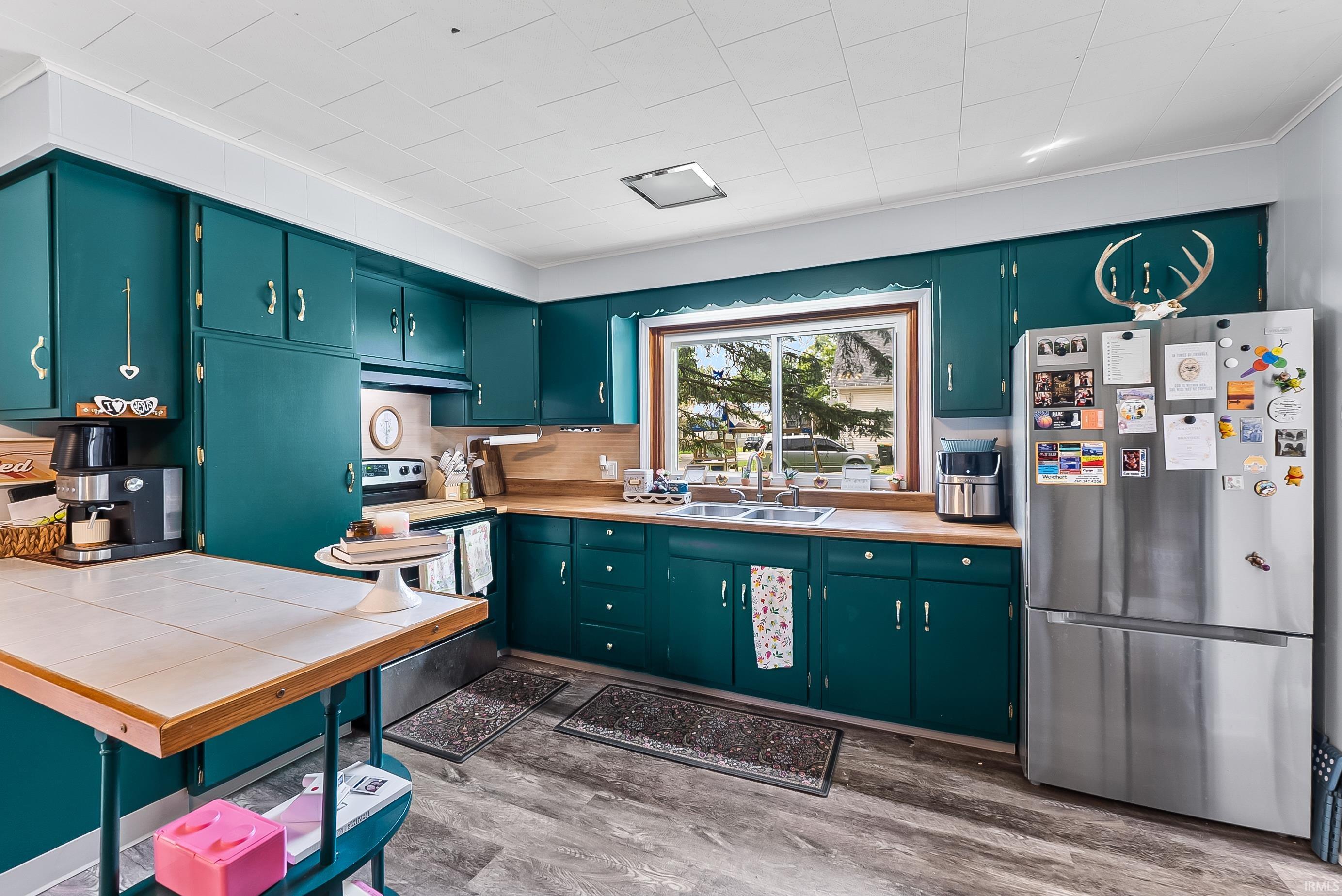 Kitchen featuring teal cabinetry, wood-finish countertops, and wood-finish flooring