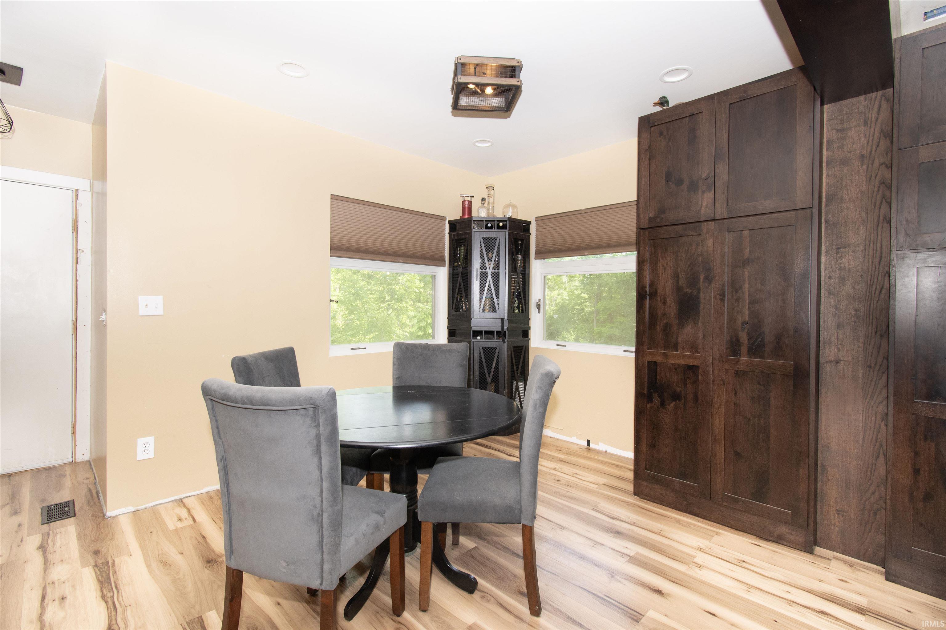 Light wood-finish flooring with floor-to-ceiling dark wood cabinetry, recessed lighting, and a corner window