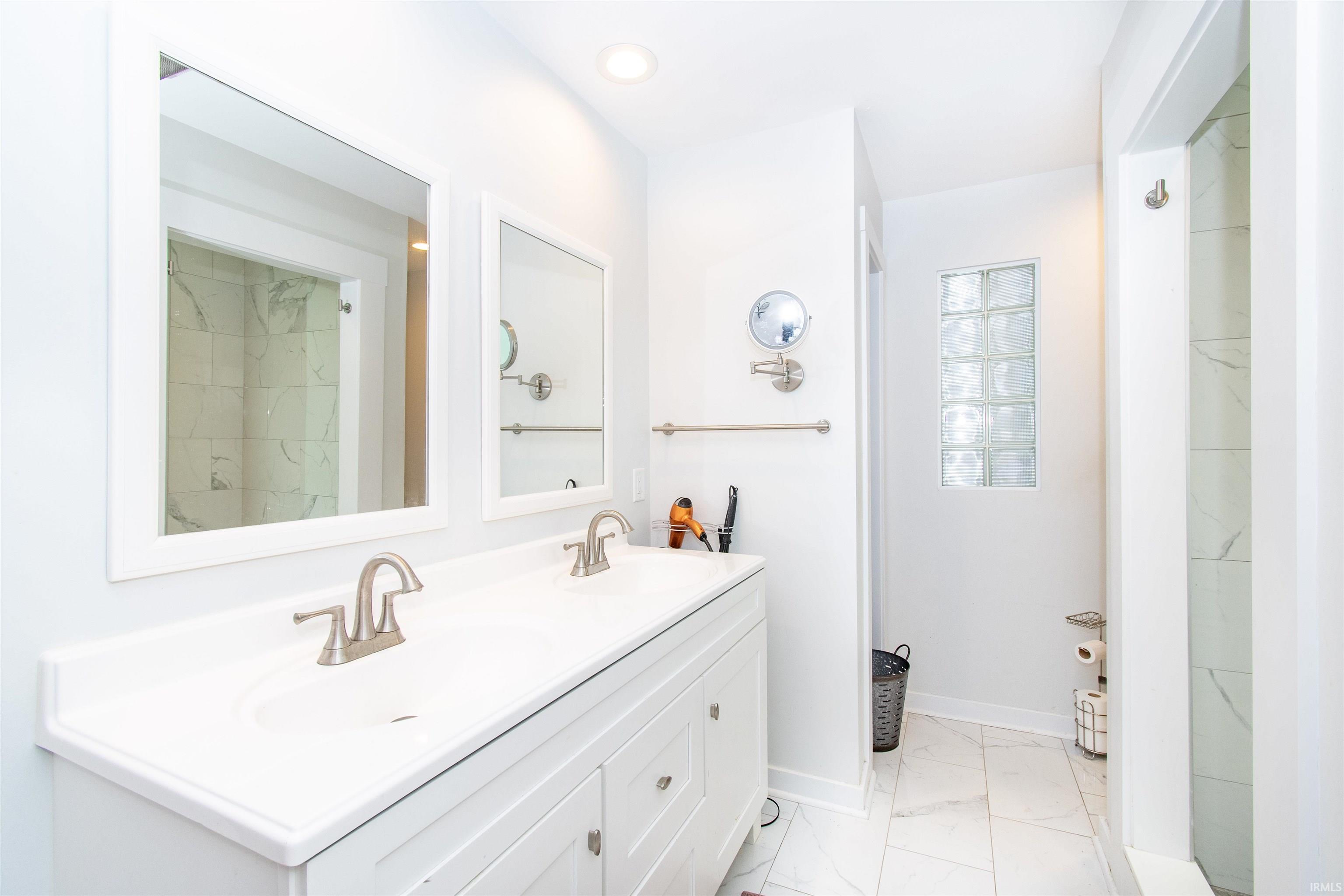 Bathroom featuring a double vanity with integrated sinks, brushed nickel faucets, and framed mirrors