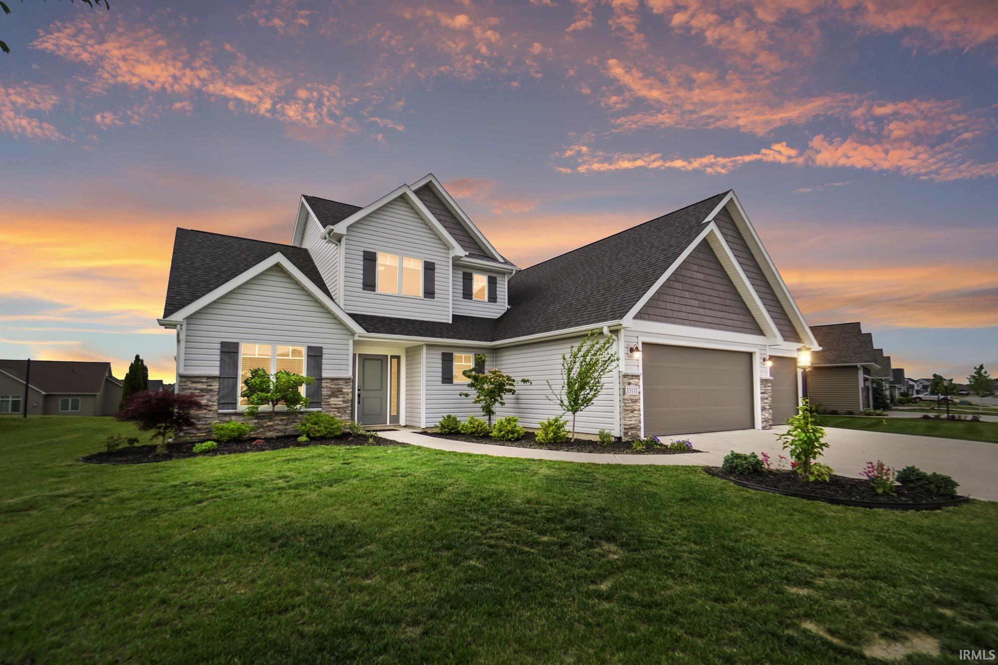 Craftsman-style exterior featuring light-colored siding, a dark shingle roof, stone accents, and dark window shutters