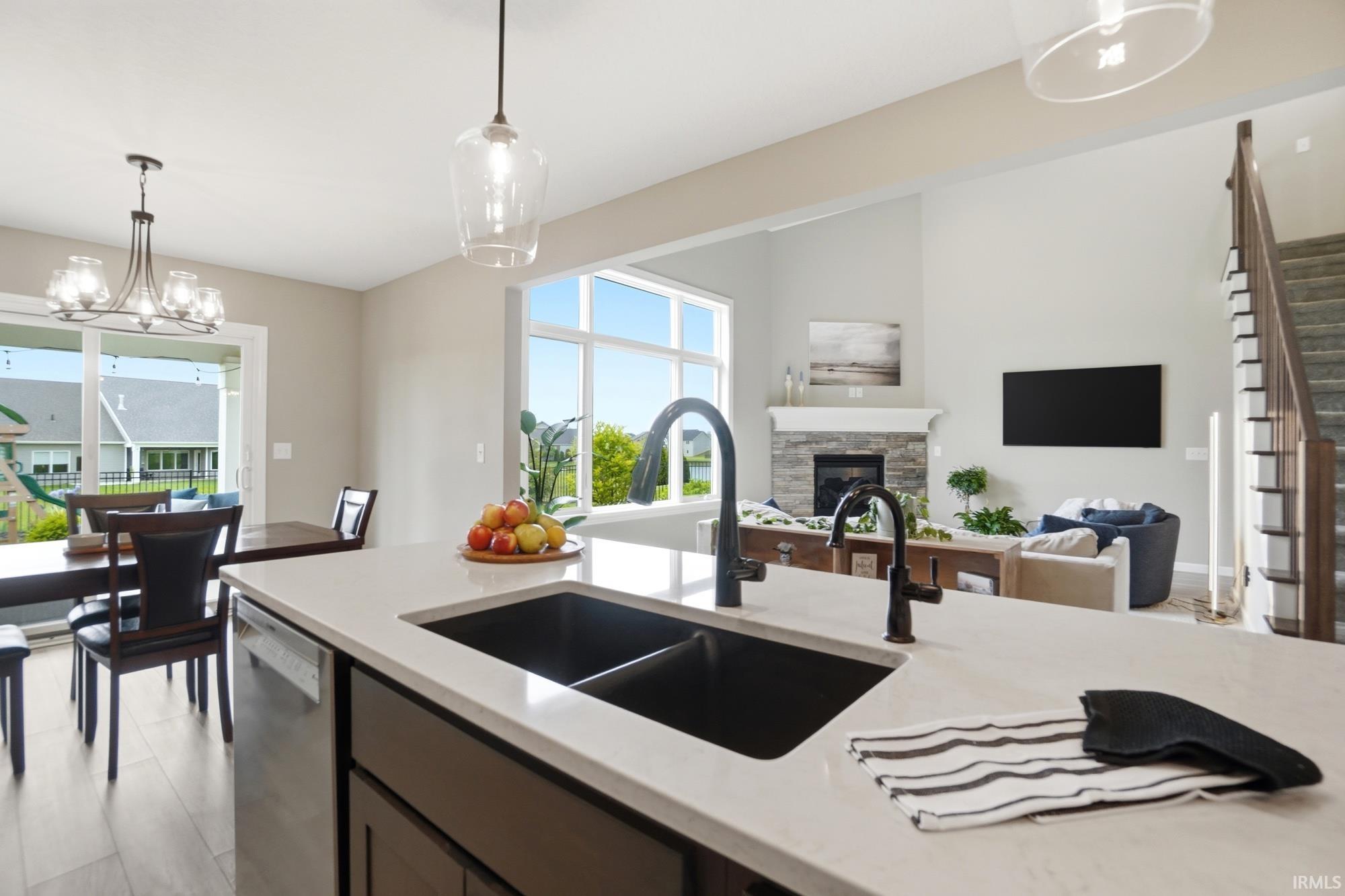 Kitchen island featuring a dual basin sink with matte black fixtures, light-toned countertop, and dark wood-finish cabinetry