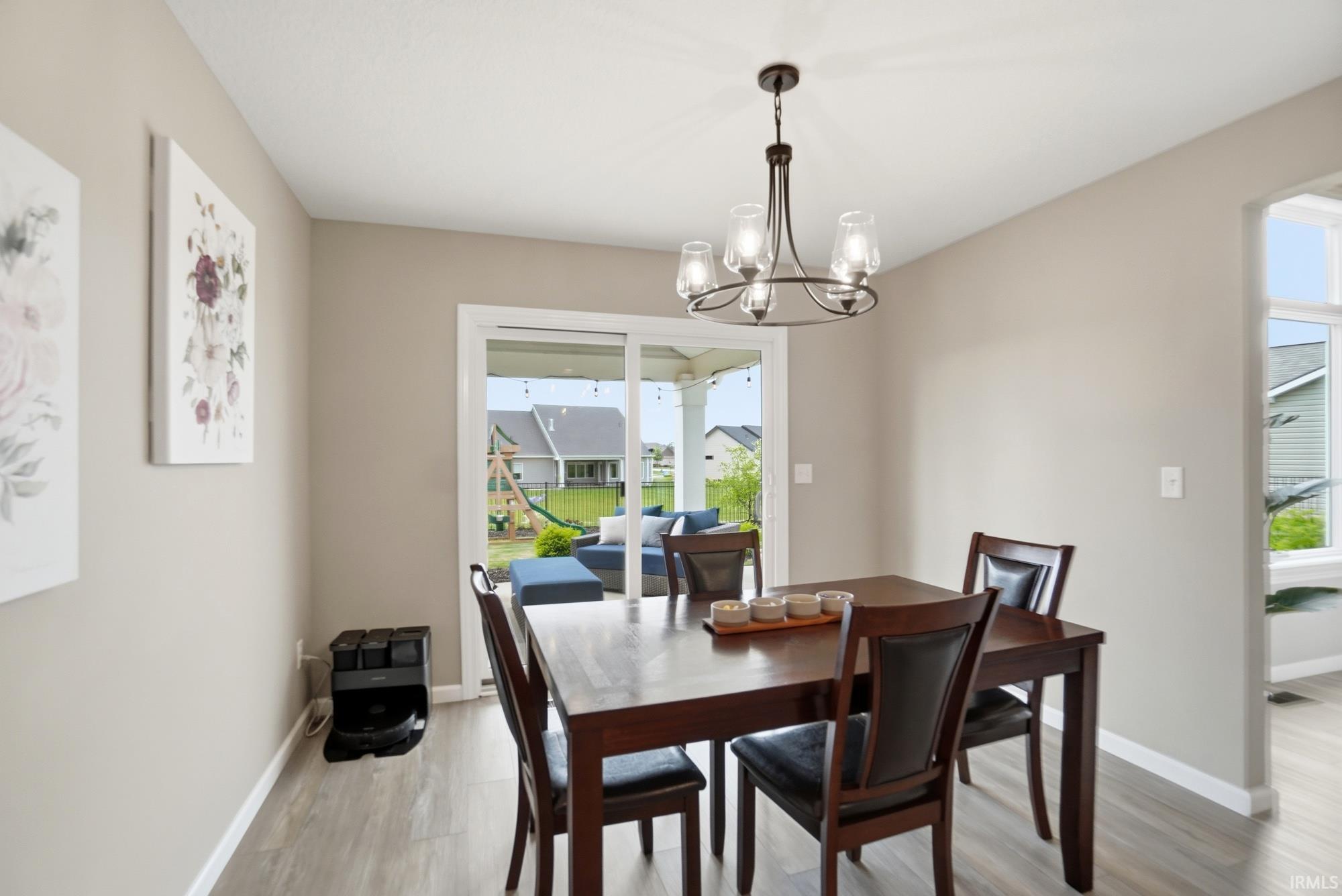 Dining area featuring wood-finish flooring, a contemporary chandelier, and light-toned walls