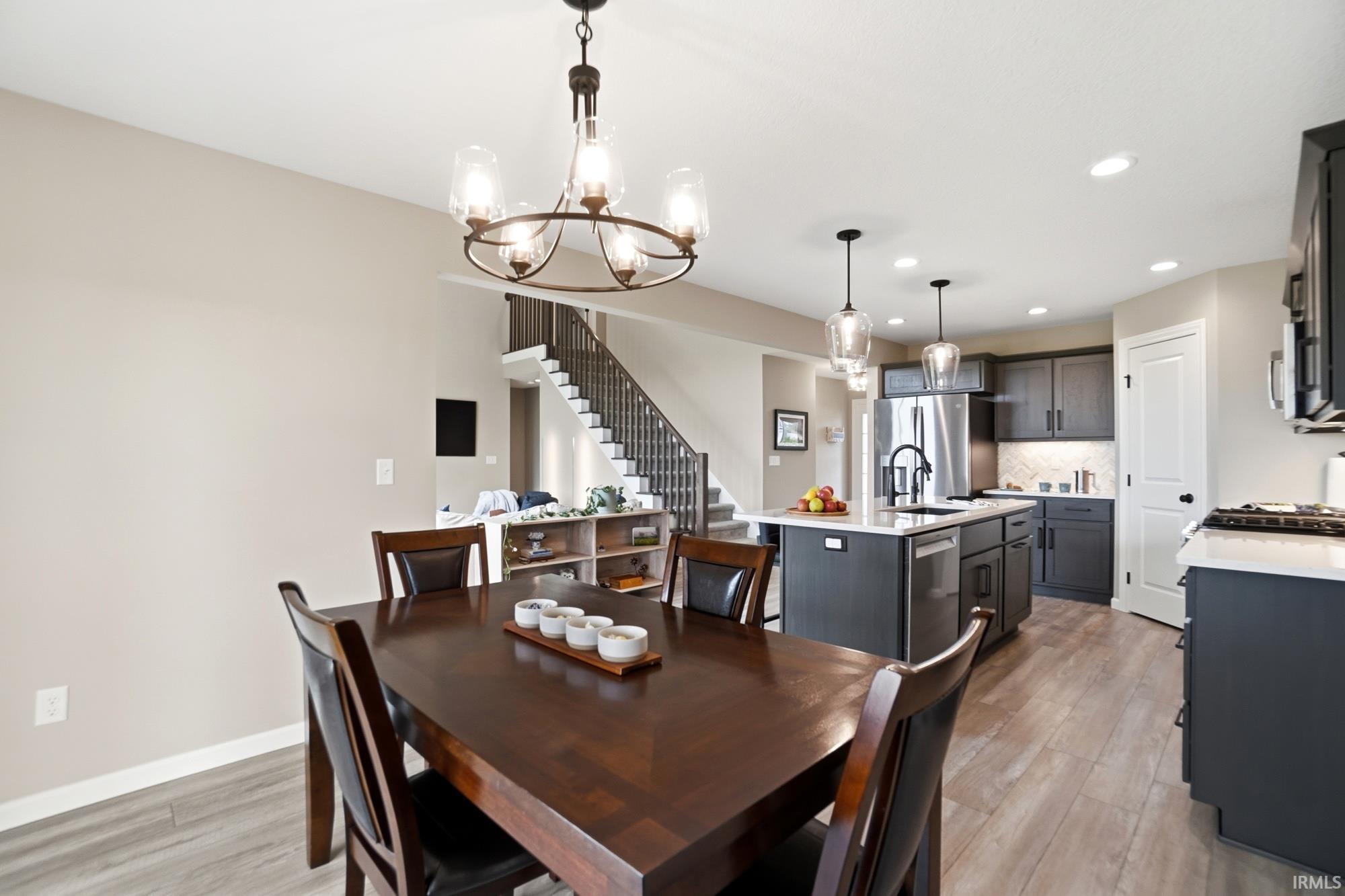 Open-concept dining area featuring a dark wood table and chairs, a five-light chandelier, and wood-finish flooring