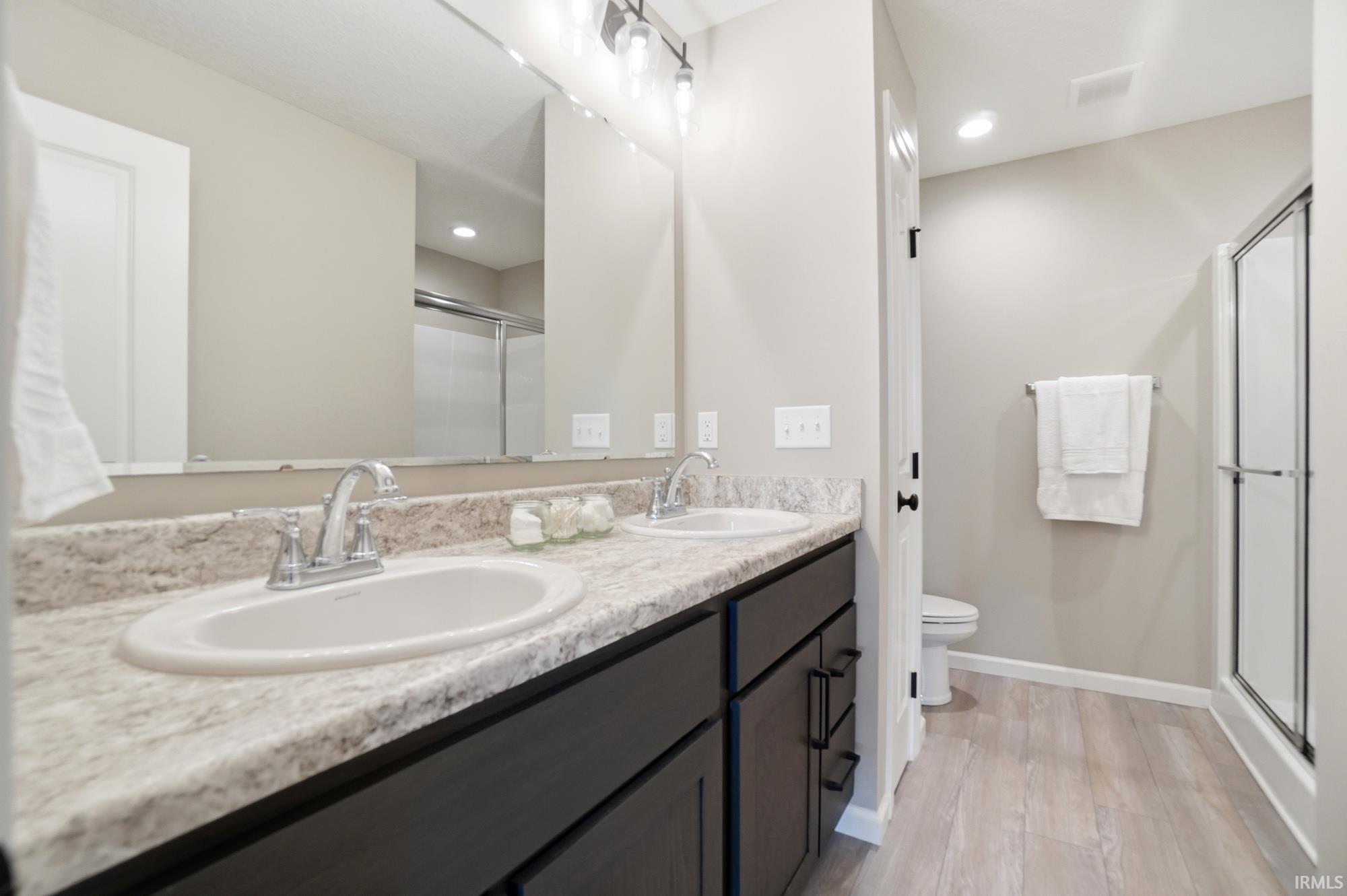 Bathroom featuring a double vanity with stone-finish countertop, dual undermount sinks, and dark wood cabinetry