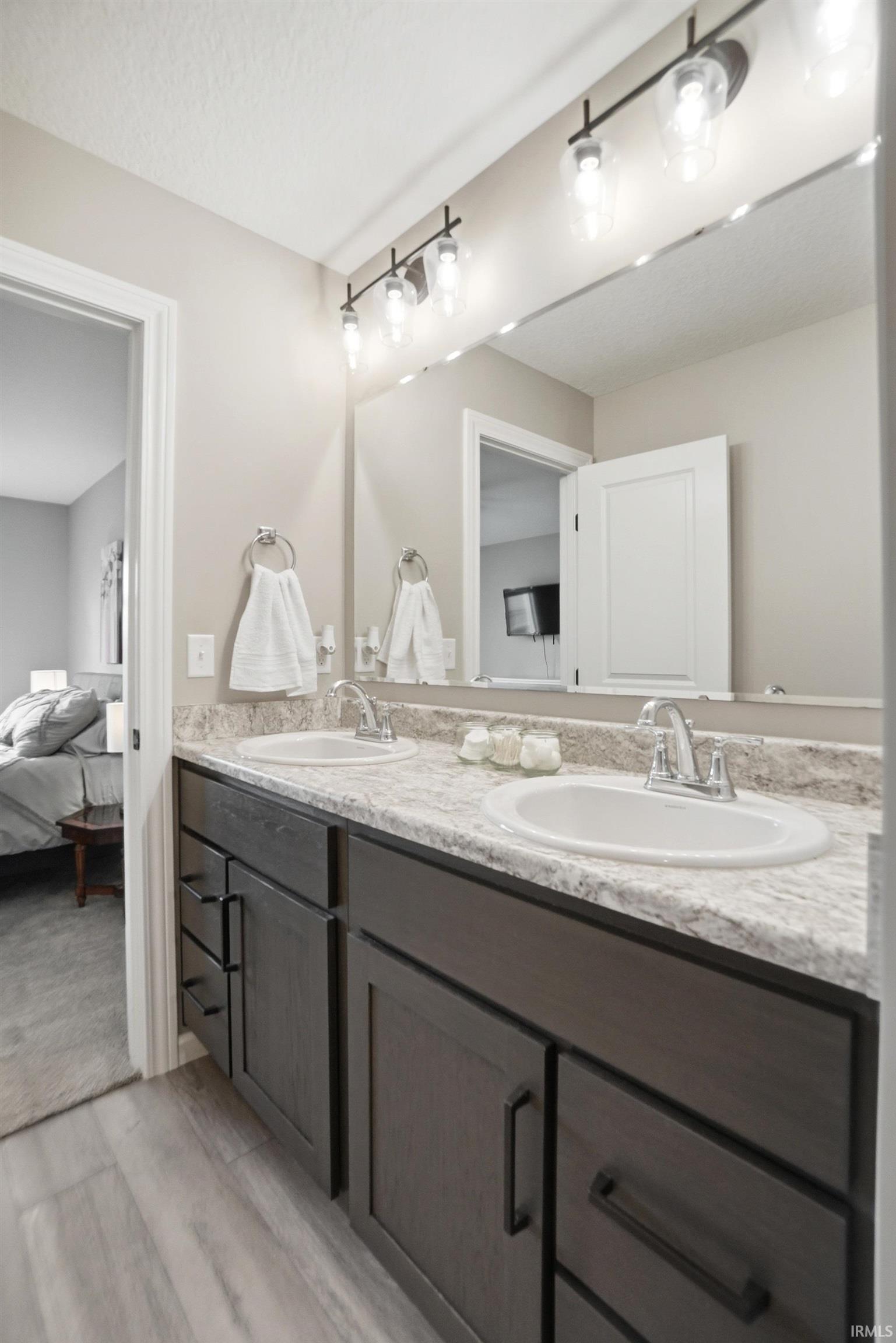 Dual vanity featuring dark wood-finish cabinetry with matte black hardware