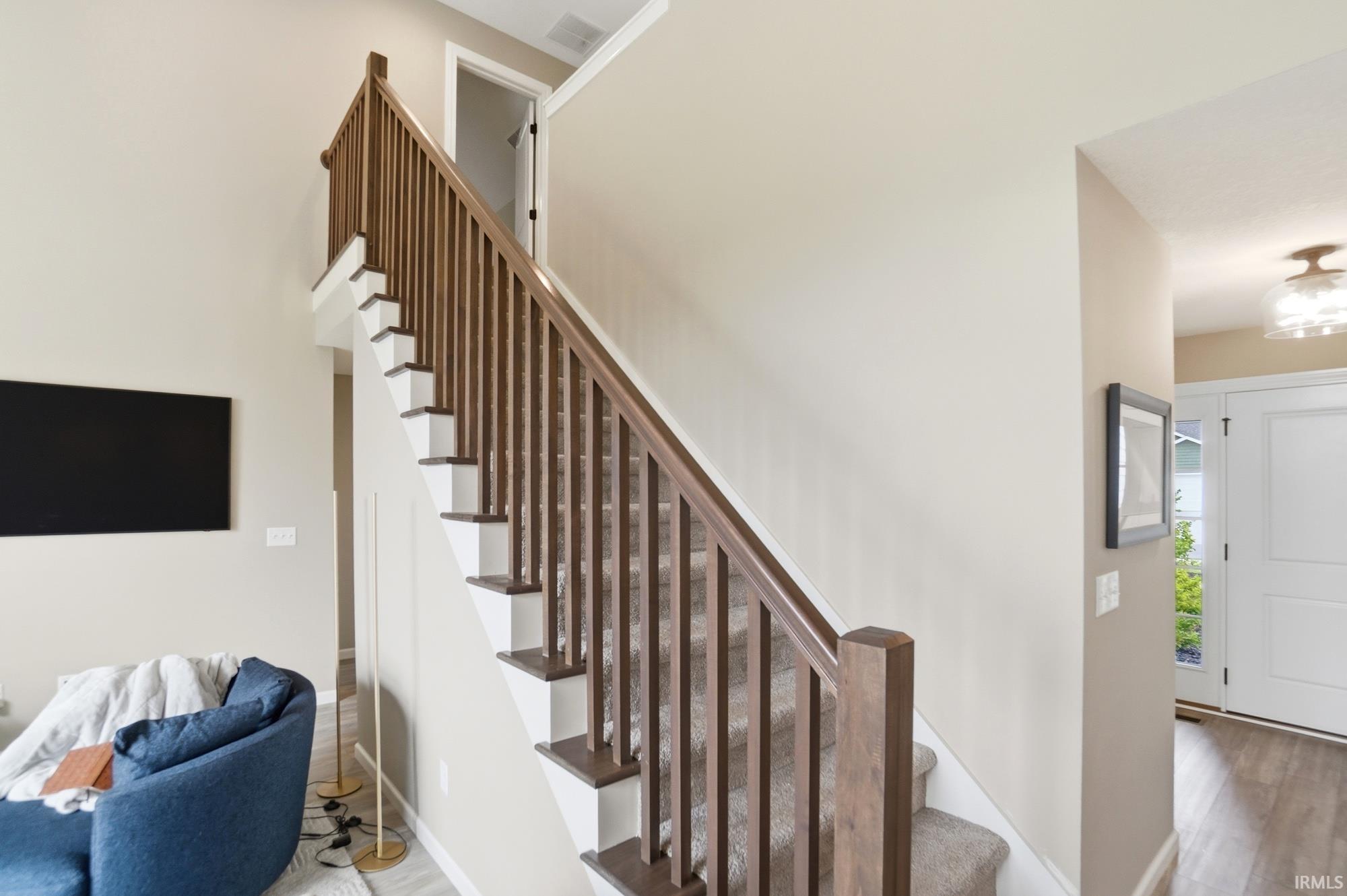 Staircase featuring wood railing and balusters, carpeted treads, and painted risers