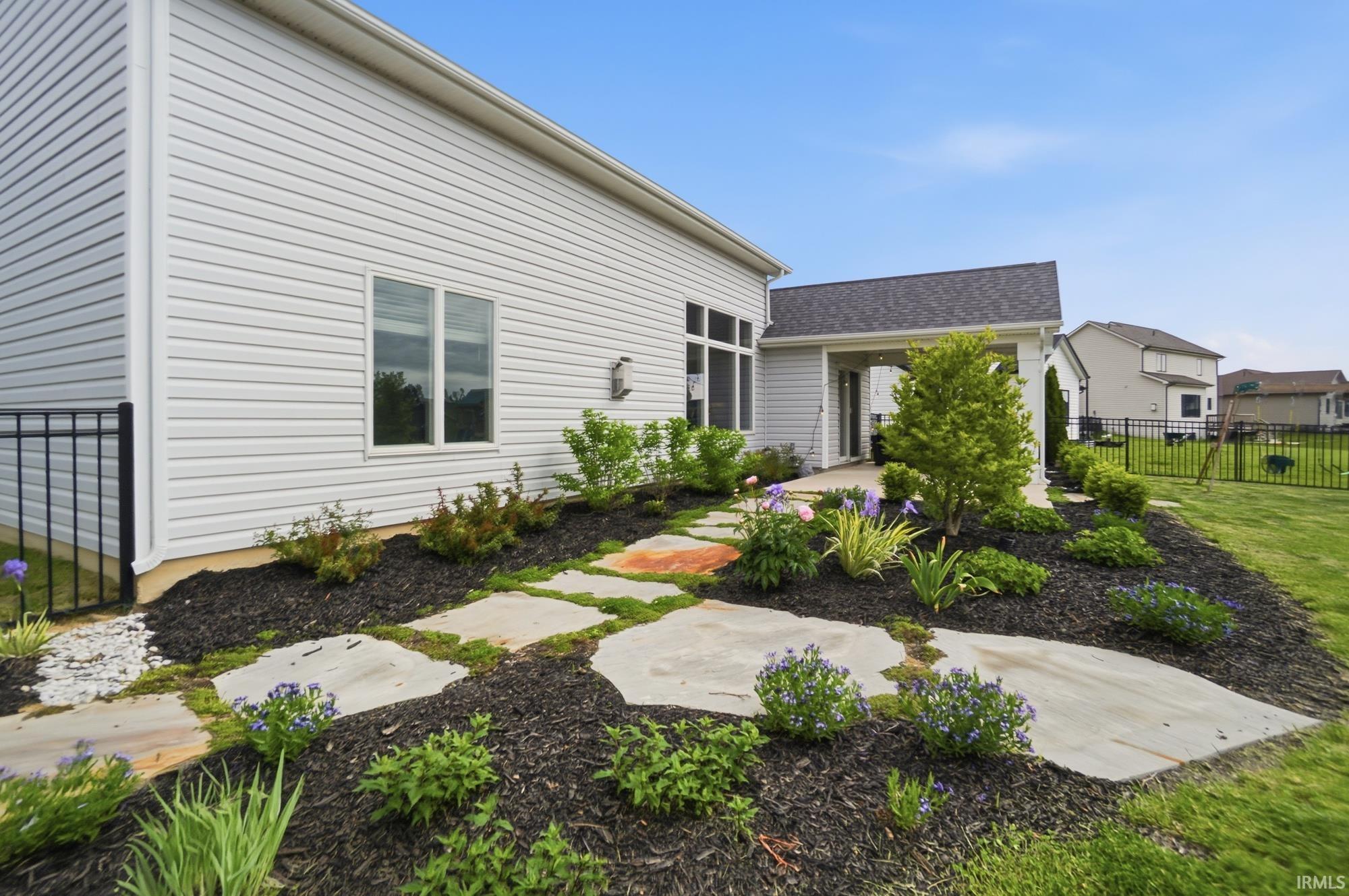 Landscaped side yard featuring irregular flagstone steps and dark mulch beds