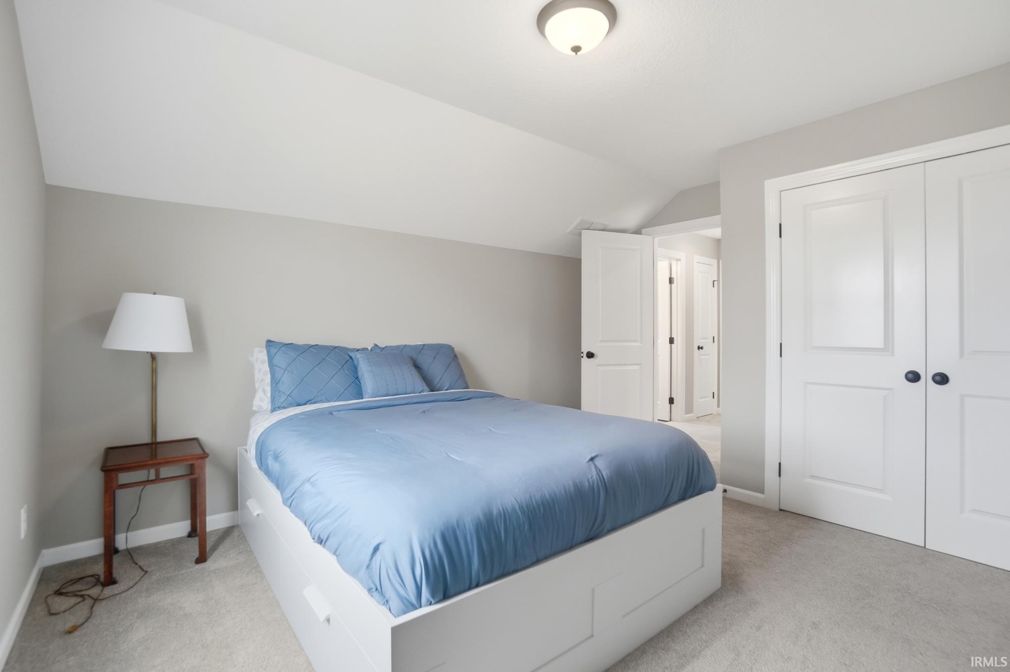 Carpeted room featuring a white paneled bi-fold closet, neutral wall paint, and an overhead flush mount light fixture