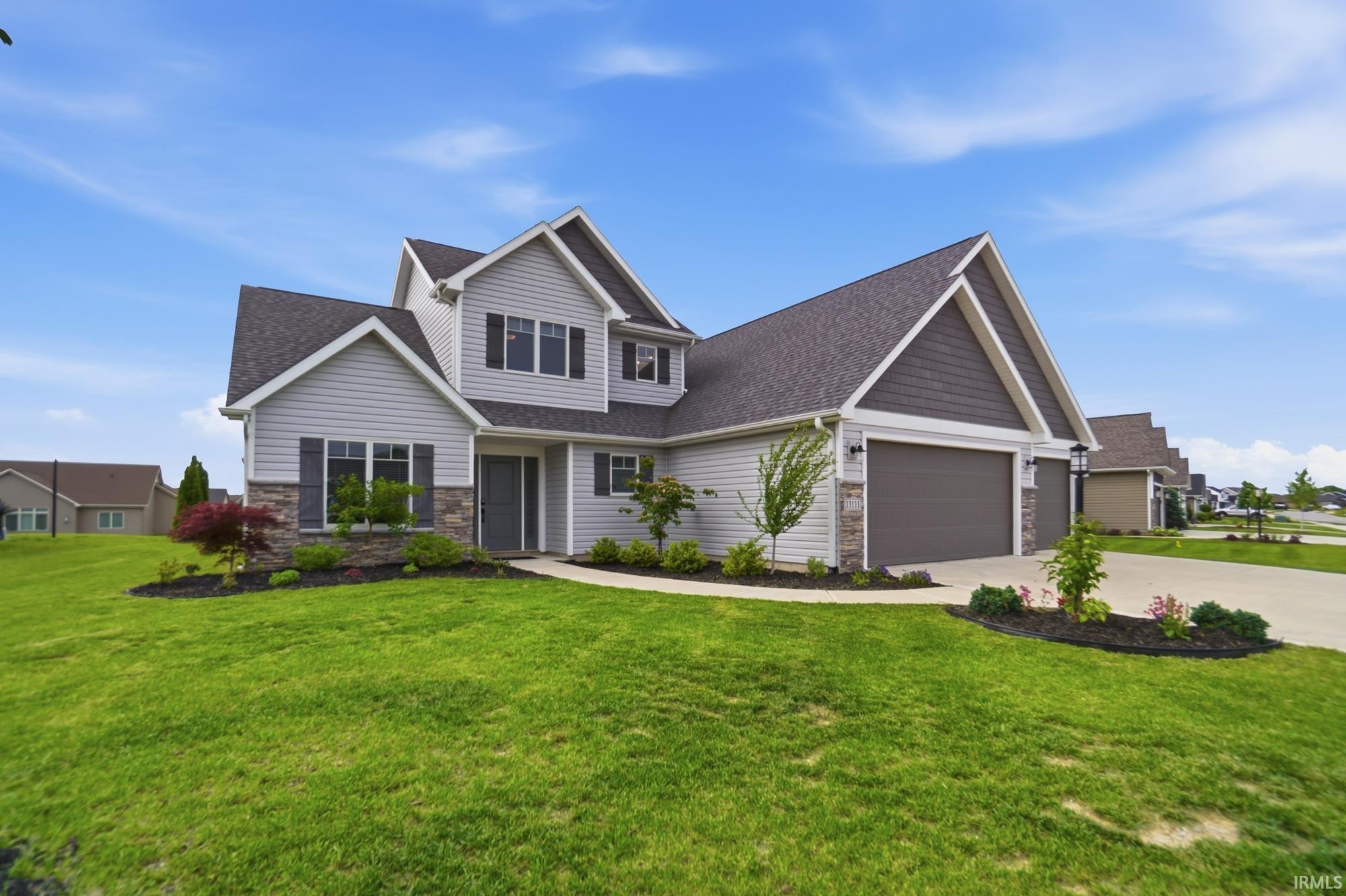 Two-story residence featuring light gray siding with dark gray shingle accents and a stone veneer foundation