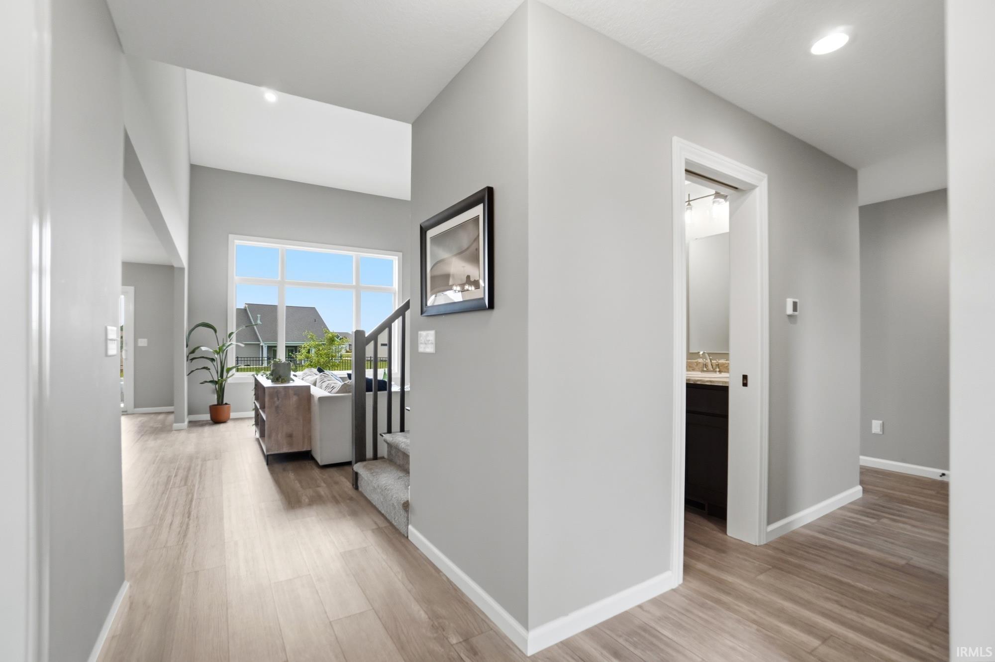 Vaulted ceilings featuring recessed lighting, large pane windows, wood-finish flooring, and a carpeted staircase with dark railings