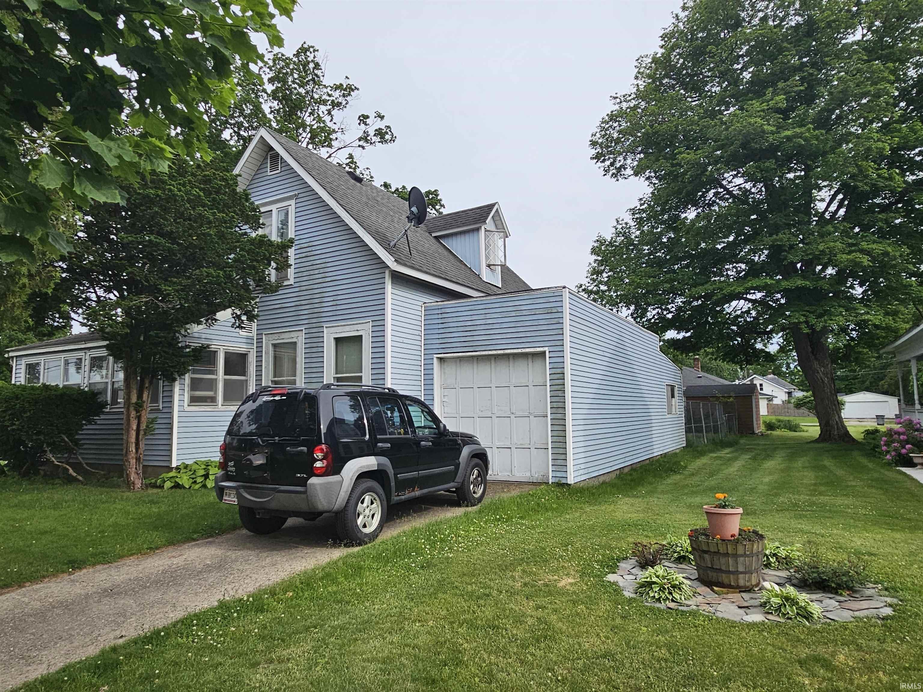 Light blue siding residence featuring a front gabled roofline and an attached garage with a white panel door