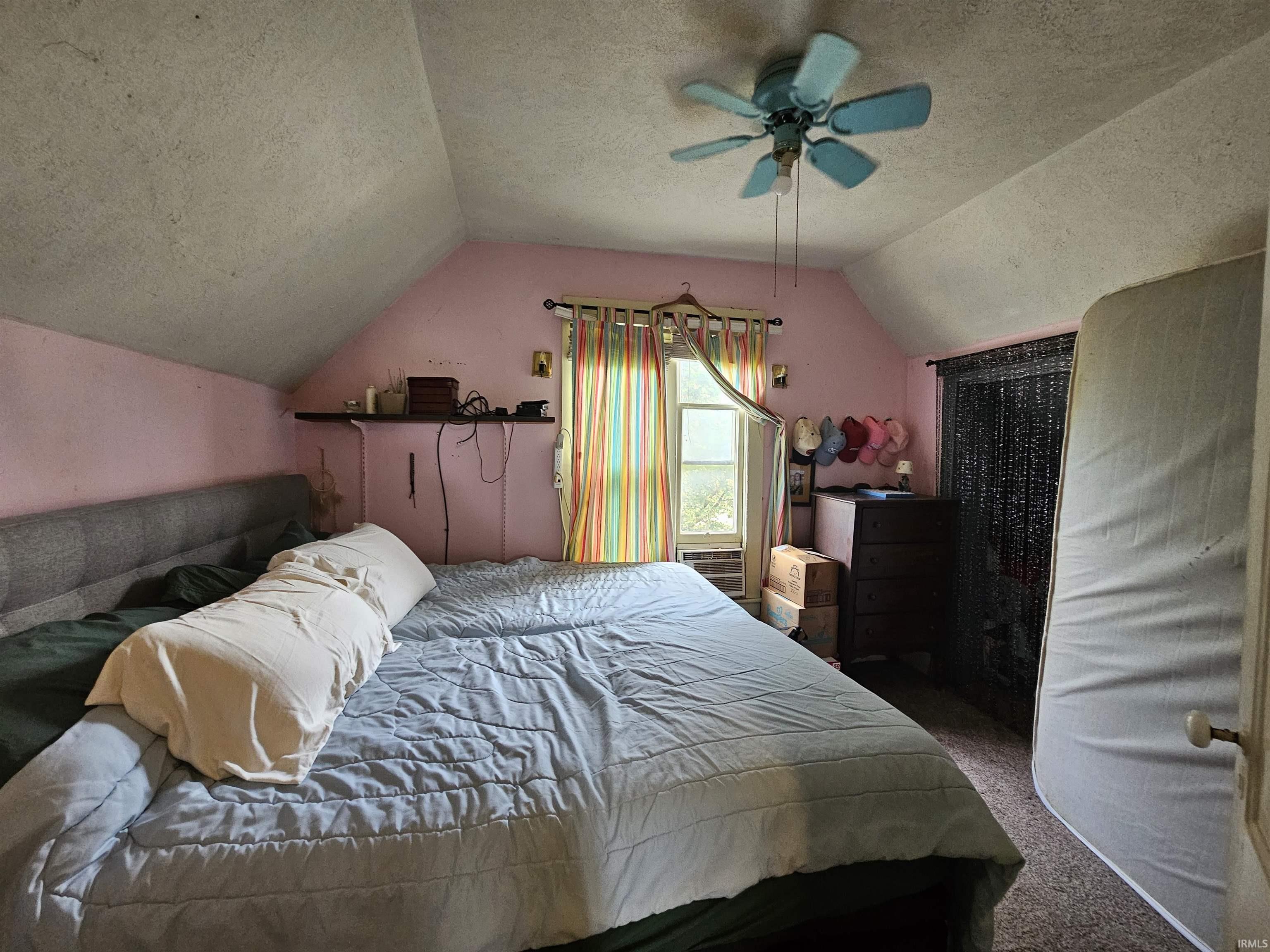 Room featuring sloped ceilings, a window, and a ceiling fan with light fixture